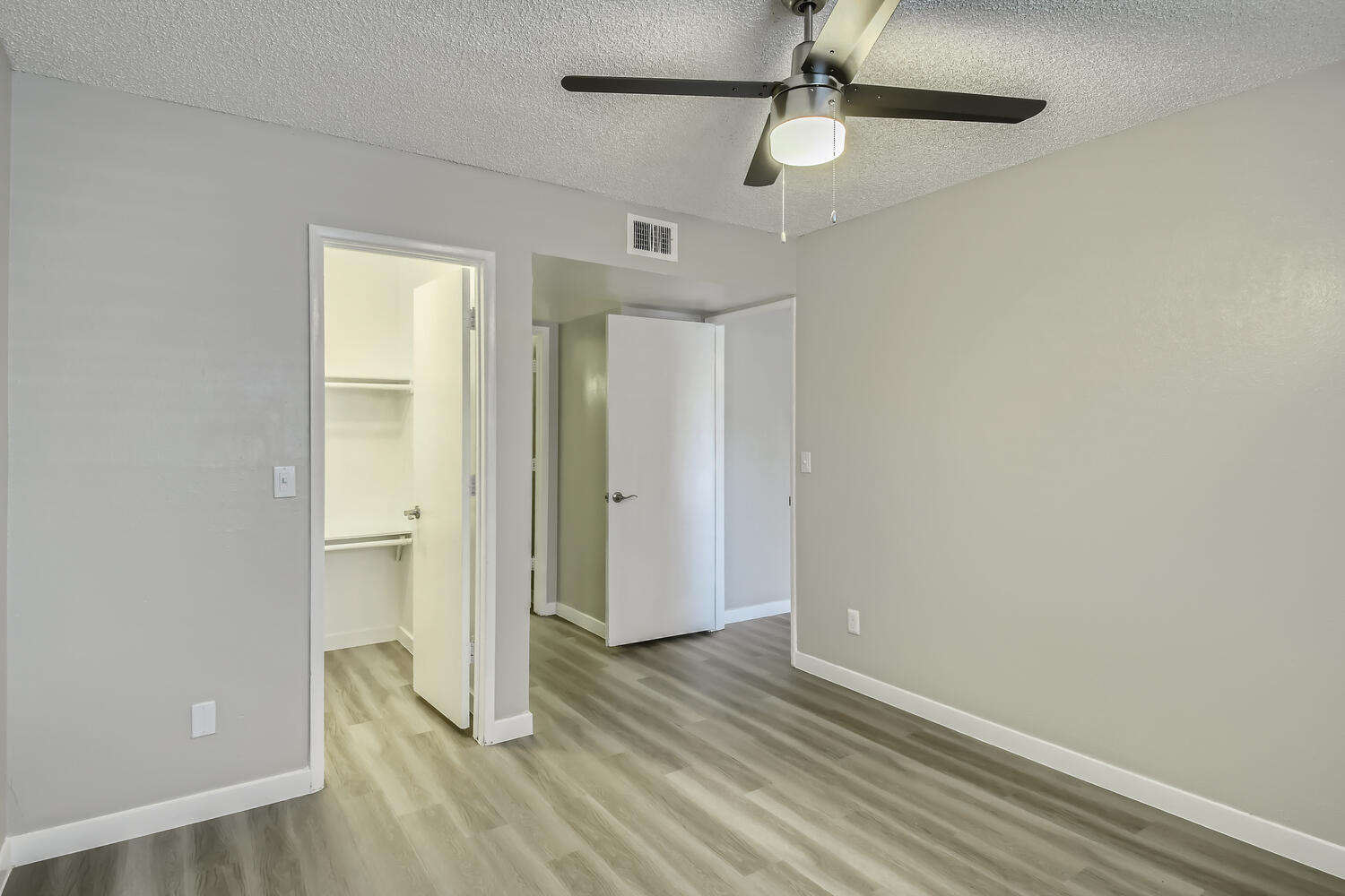 An apartment bedroom with a closet, wood-style flooring, and a ceiling fan at Rise North Ridge.