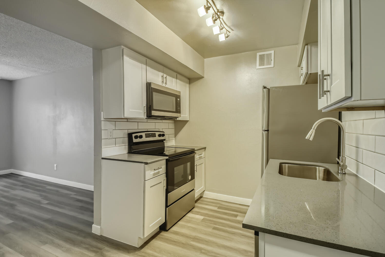 An apartment kitchen with shaker cabinets and a living area nearby at Rise North Ridge.