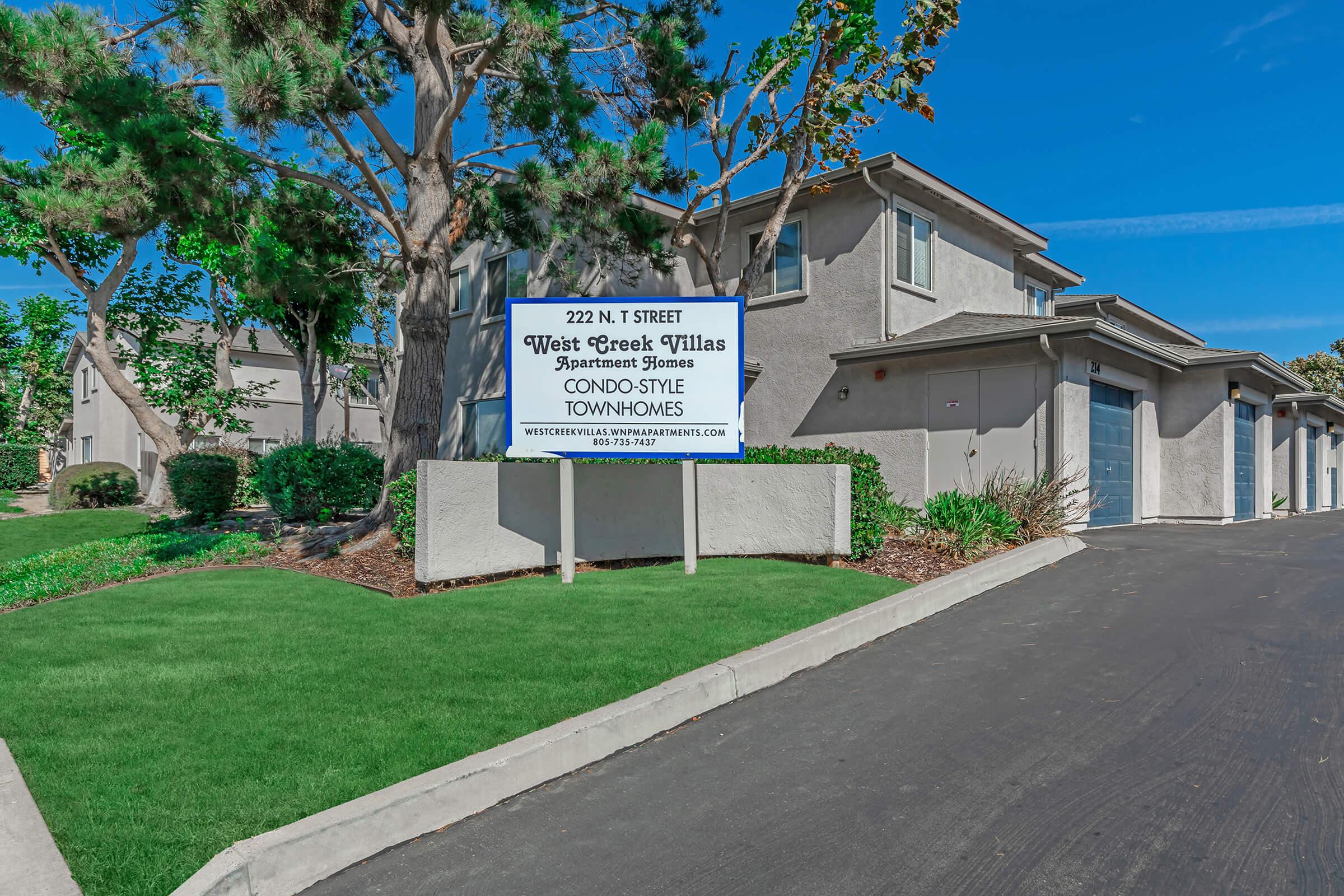 a house that has a sign on the side of a road