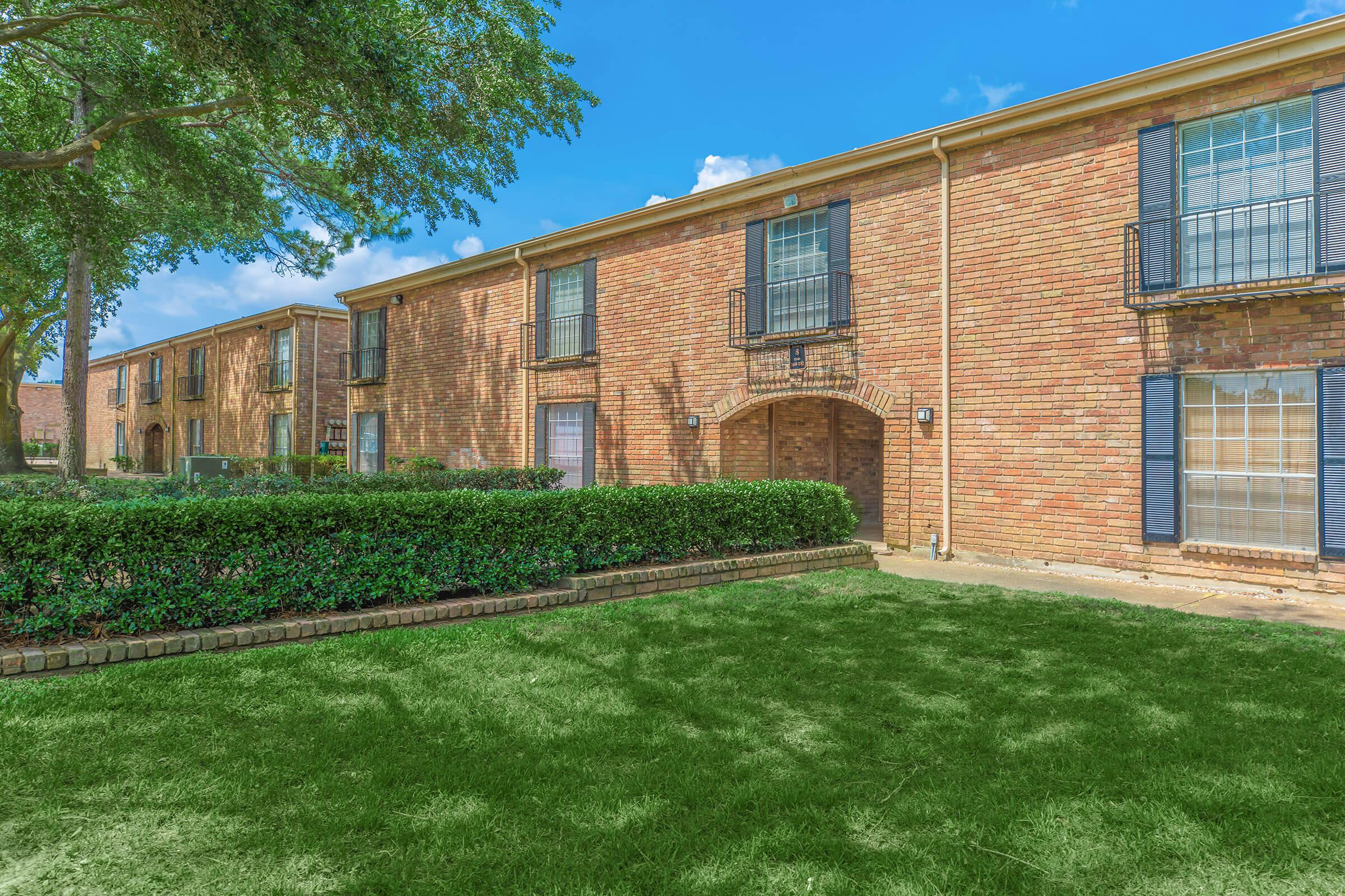 a large brick building with green grass in front of a house