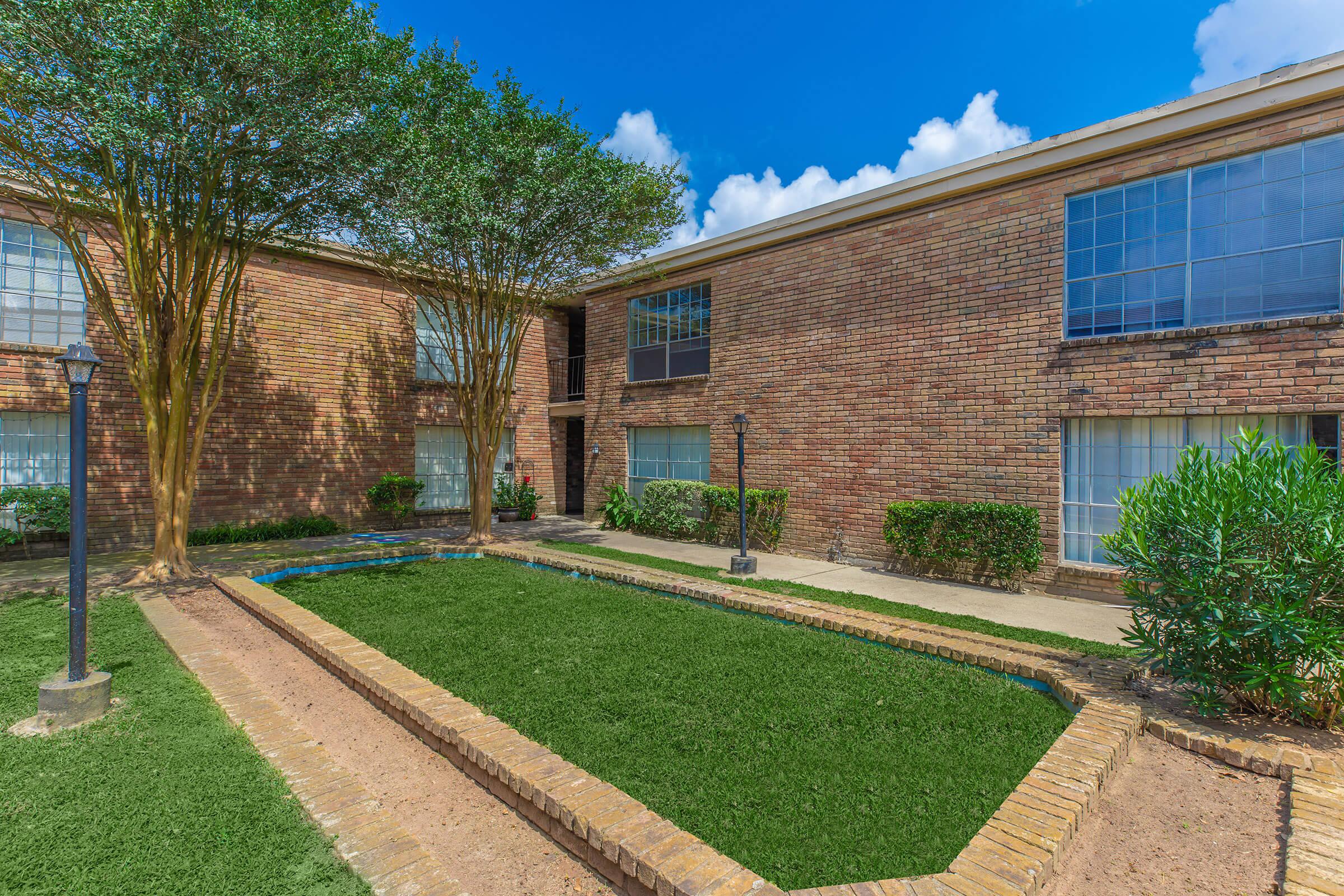 a large brick building with grass in front of a house