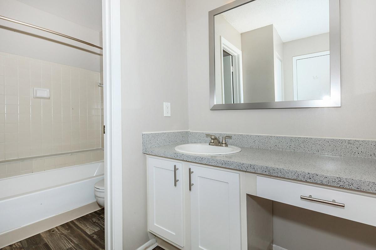 a white sink sitting under a mirror