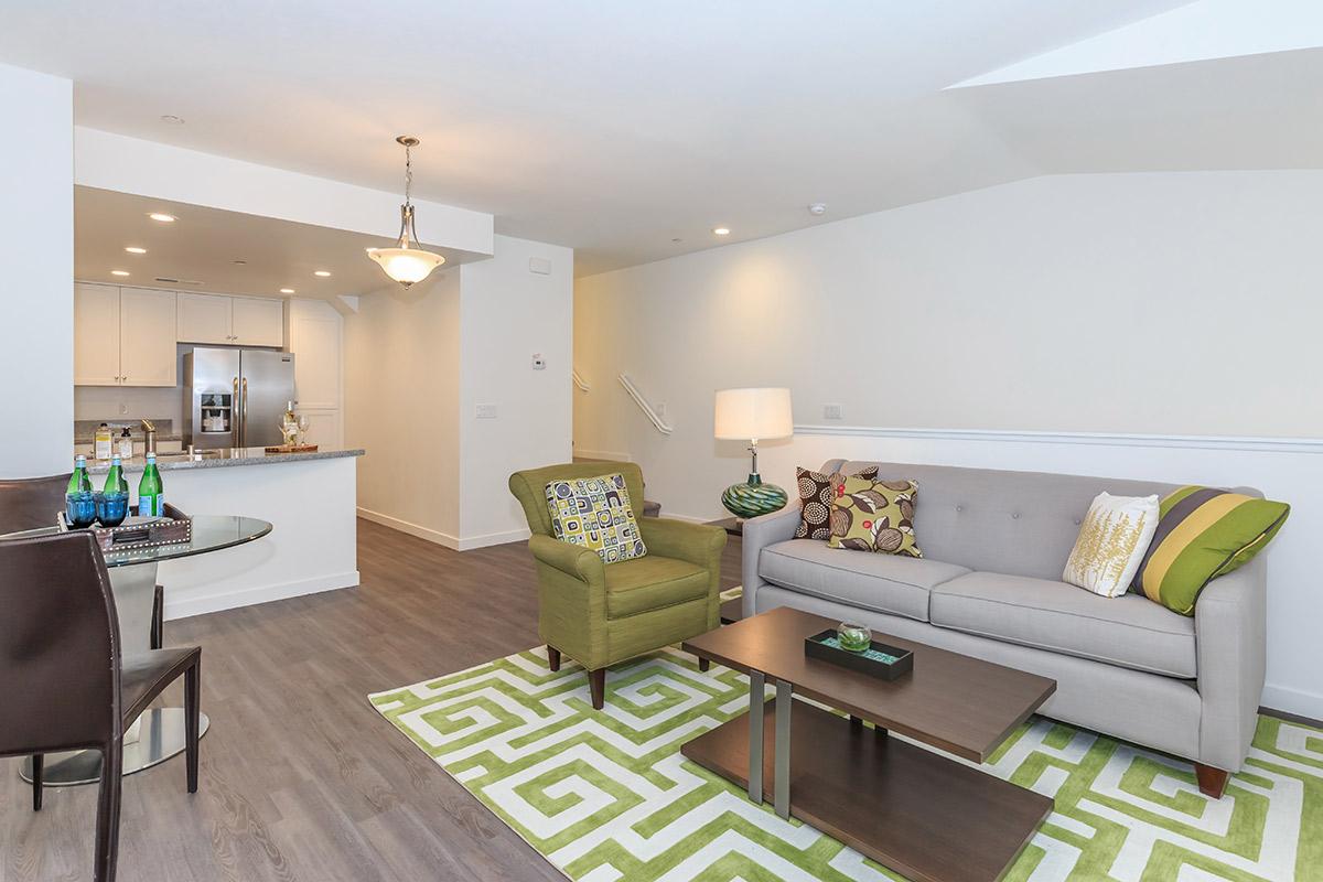 2-Bedroom Townhomes in Chula Vista, CA - Contessa at Otay Ranch - A Modern Living Room with a Gray Sofa, a Wooden Coffee Table, and Wood-Style Flooring.