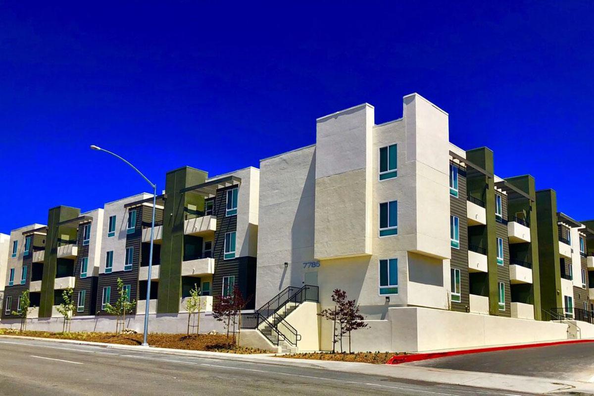 Modern multi-story apartment building with a clean design, featuring a combination of white and dark green facades.