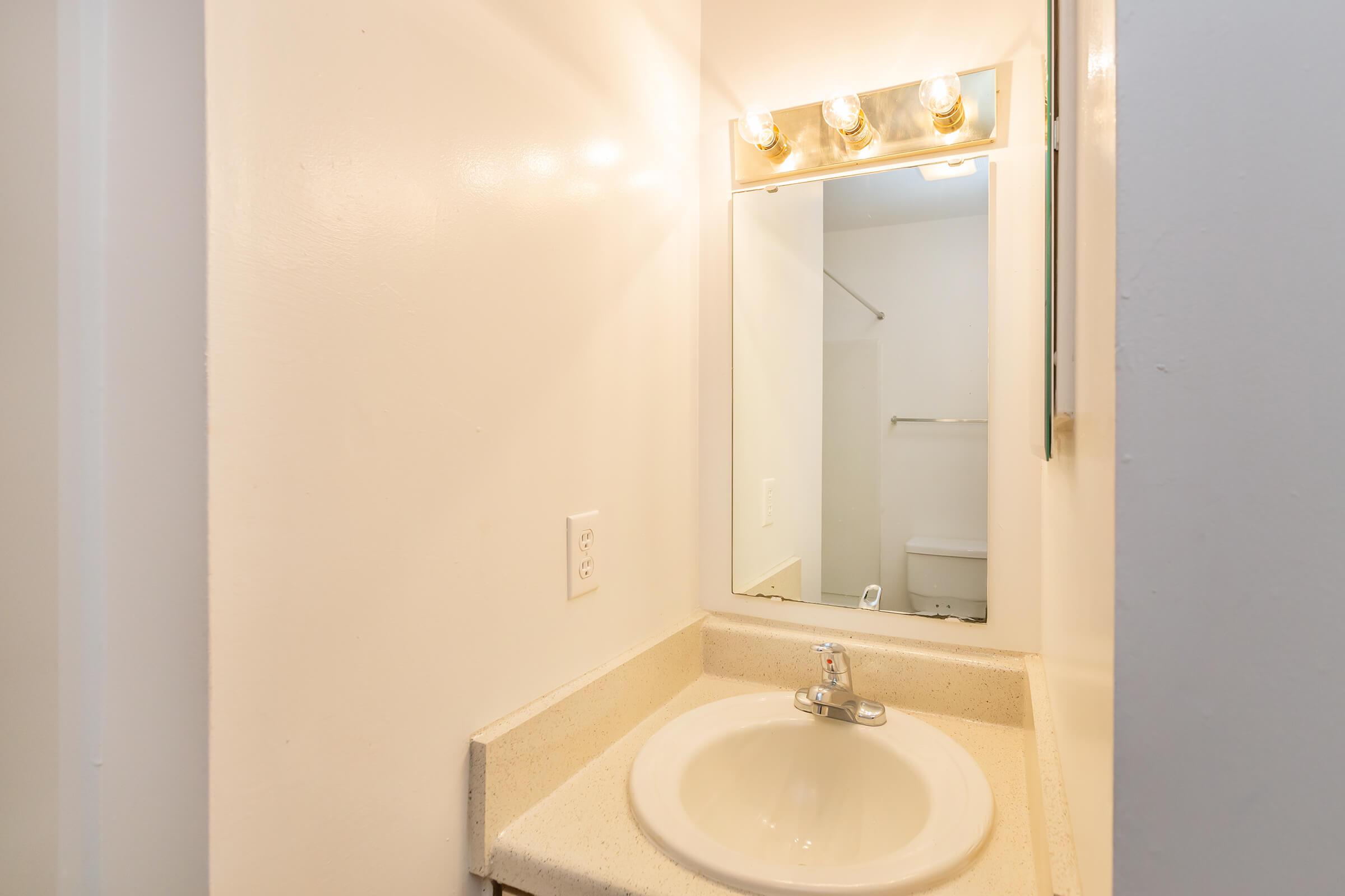 a white sink sitting under a mirror