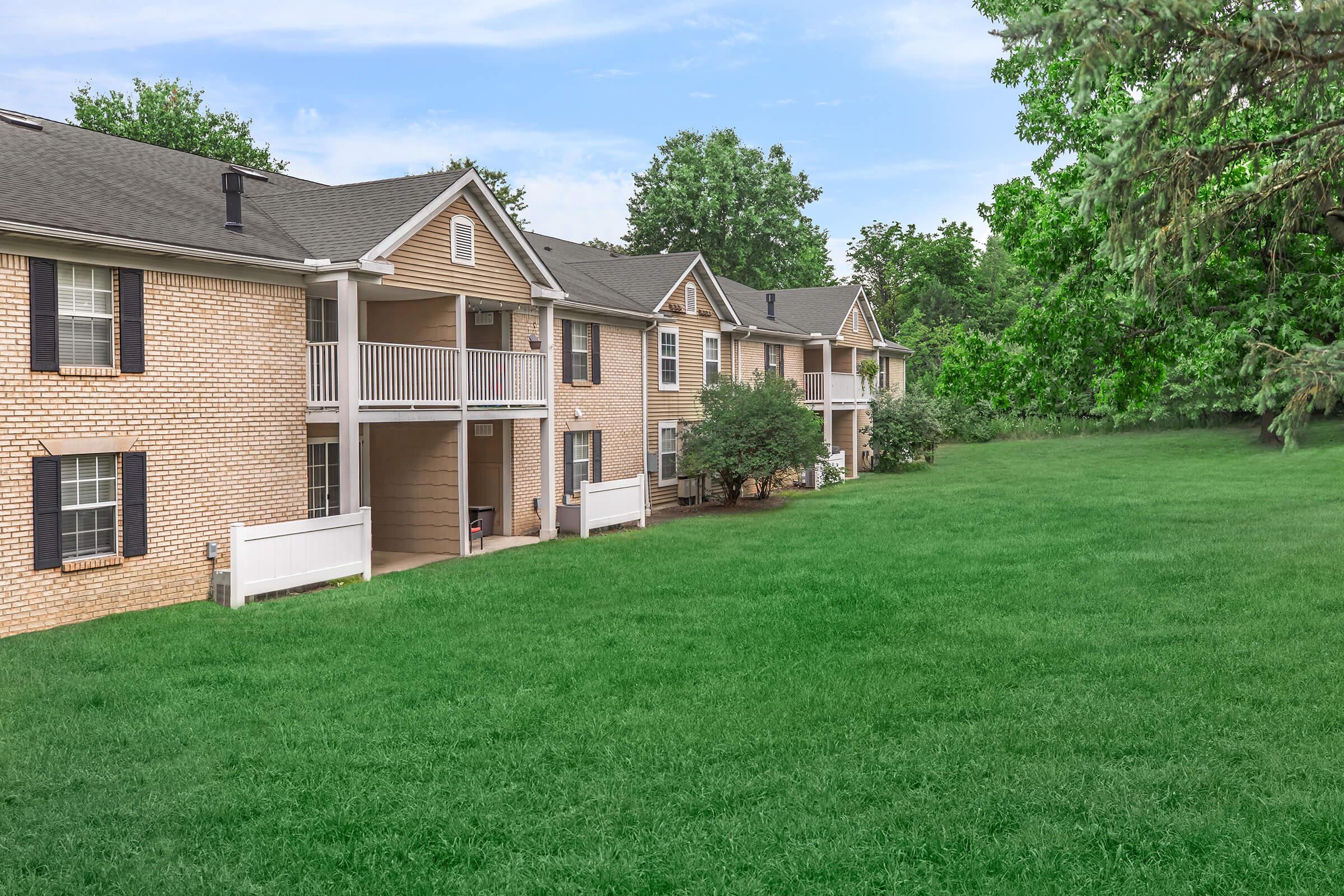 a large brick building with green grass in front of a house