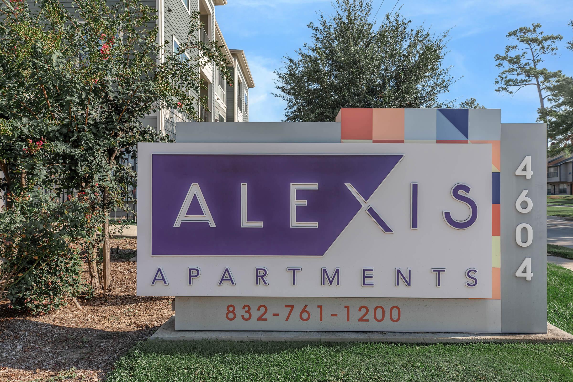 Sign for Alexis Apartments, featuring large purple text on a white background. The sign includes the phone number 832-761-1200 and the address 4604. Colorful geometric shapes are displayed at the top, with well-maintained landscaping in the foreground.
