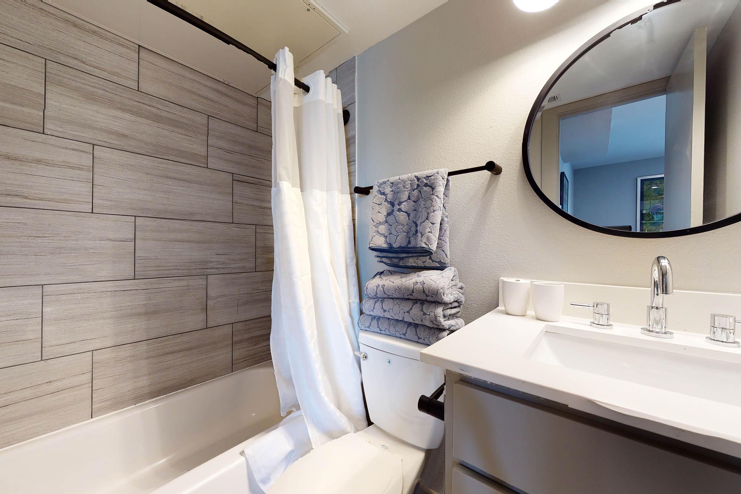 a furnished bathroom with a white shower curtain