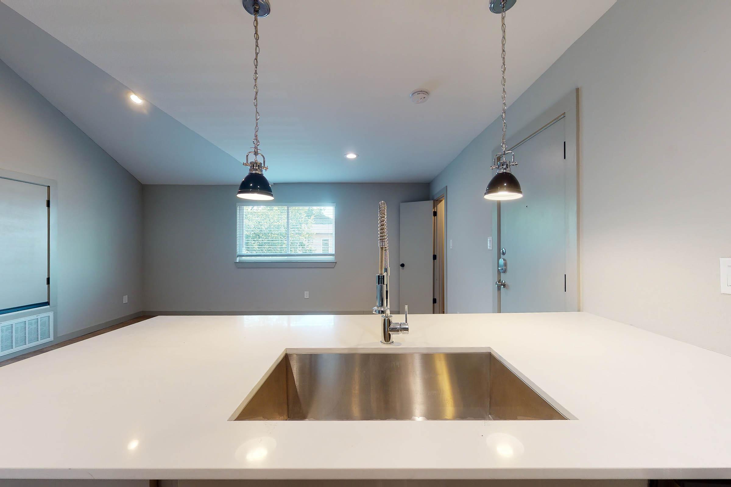 a kitchen sink with low hanging lights