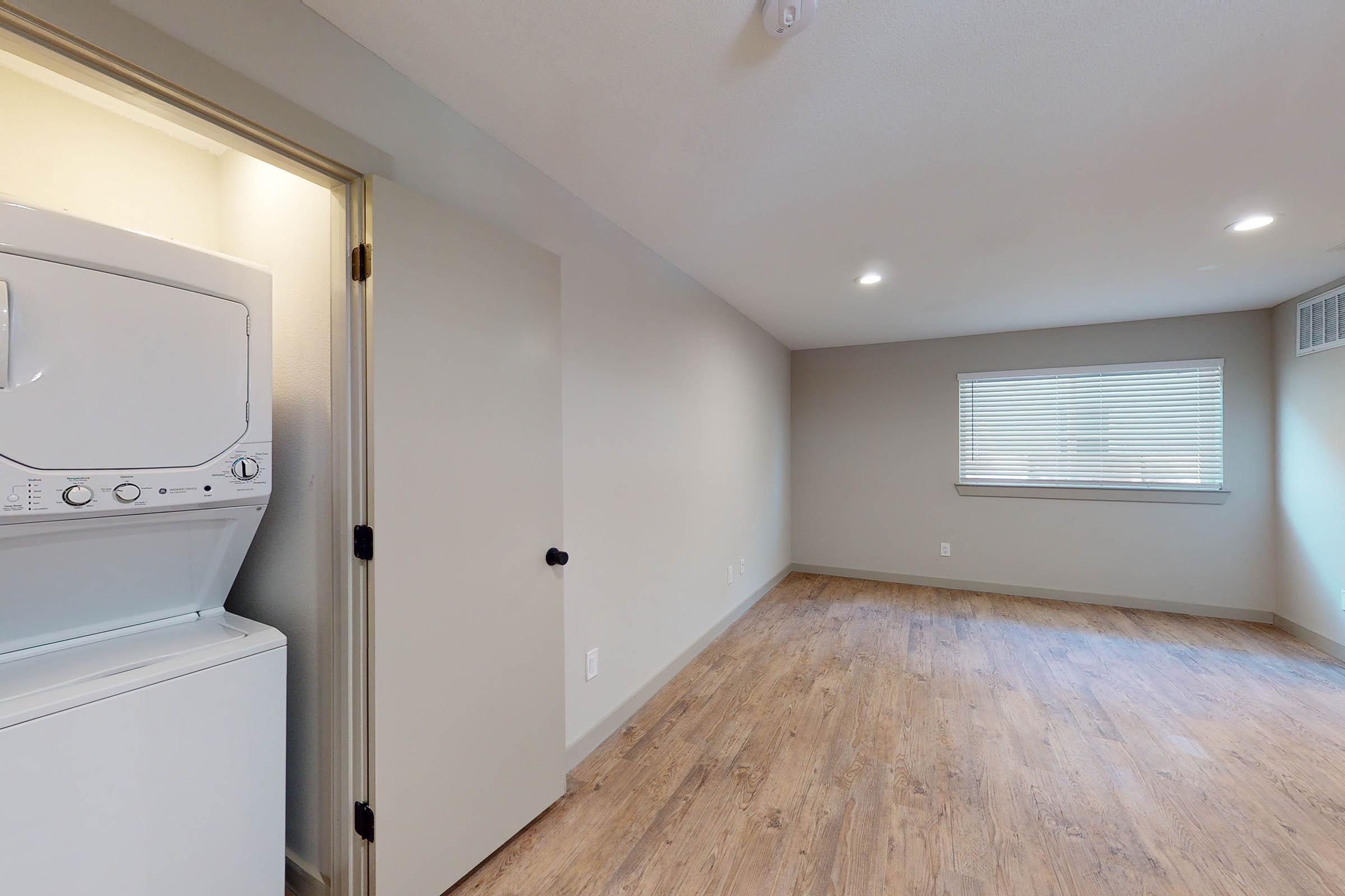 an unfurnished living room with a stacked washer and dryer