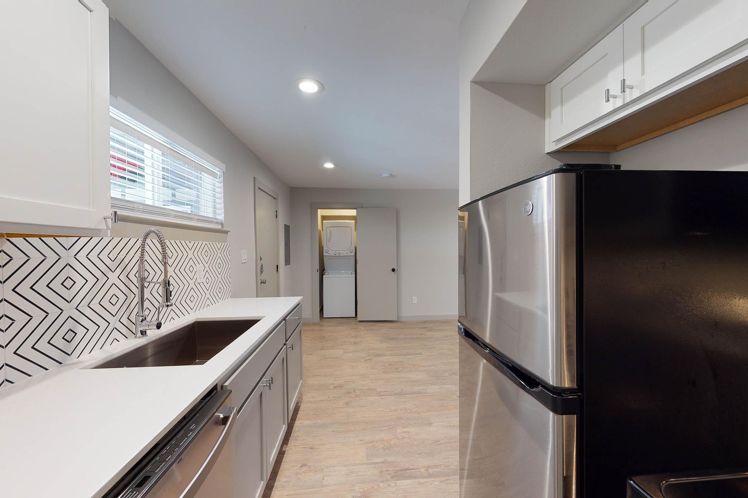 an unfurnished kitchen with white cabinets