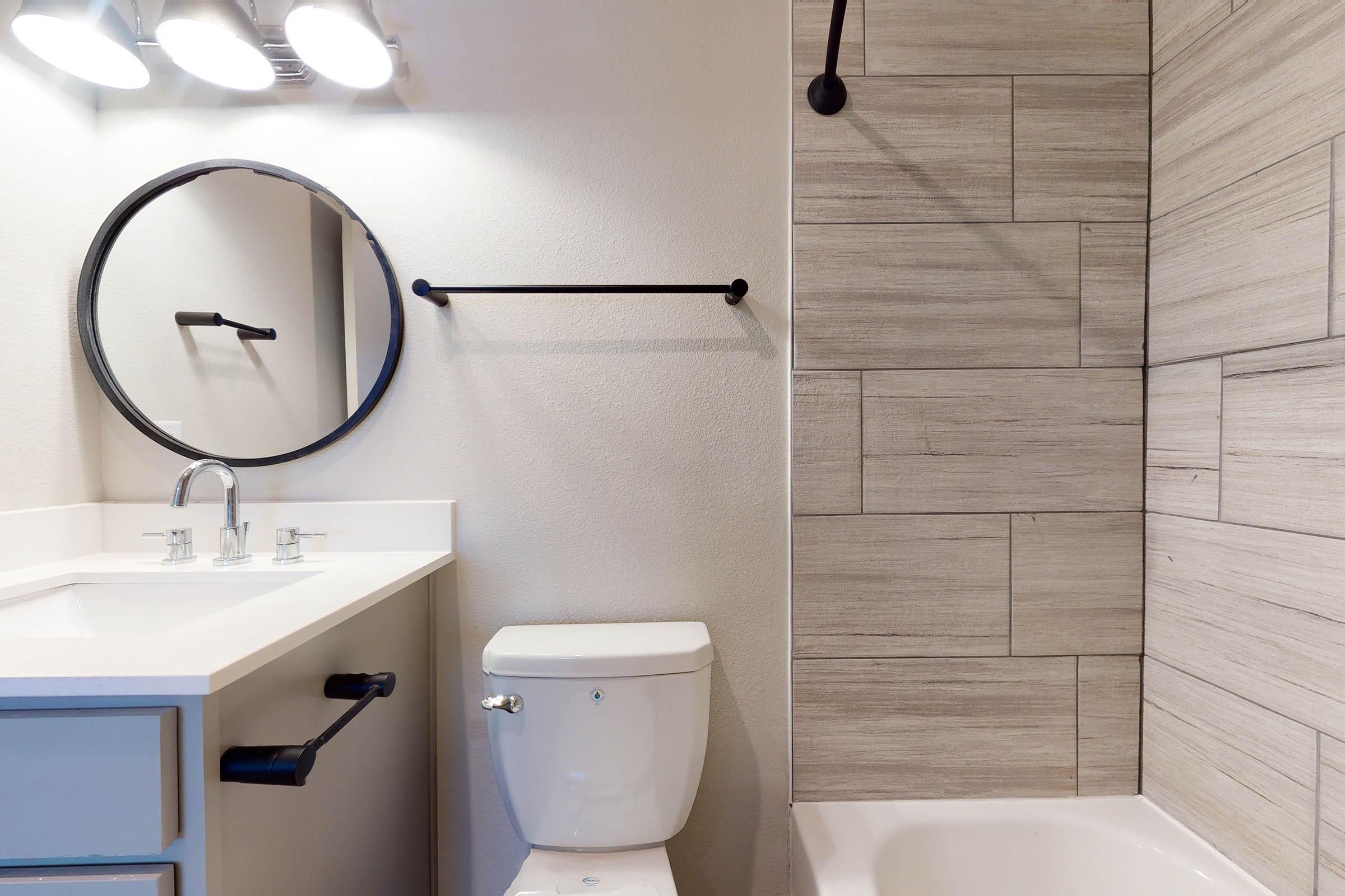 a vacant bathroom with tan shower tiles