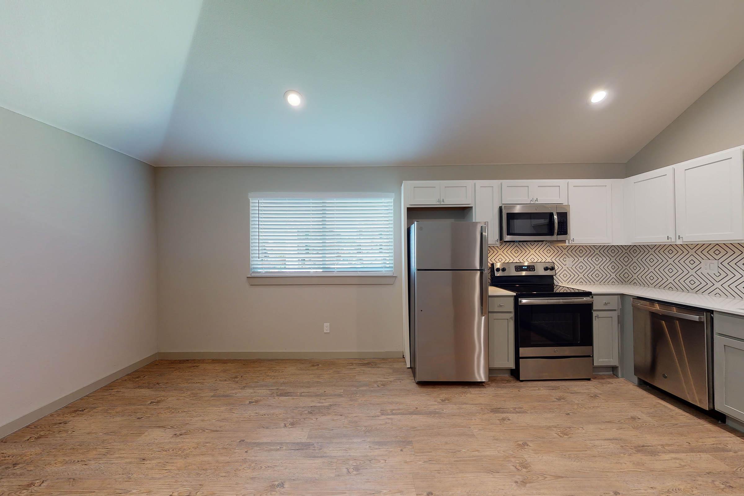 a vacant kitchen and dining room with wooden floors