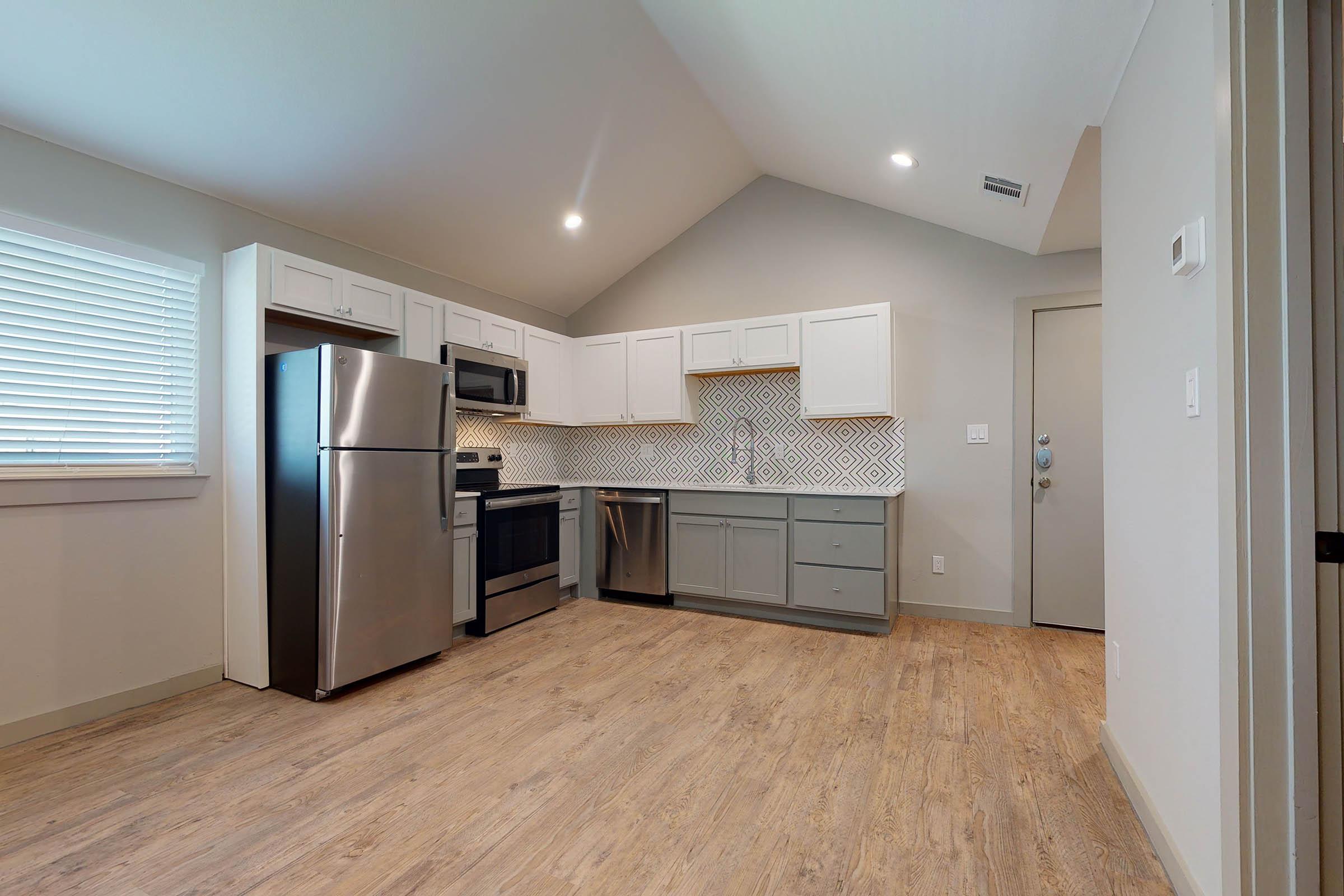 a vacant kitchen and living room with stainless steel appliances