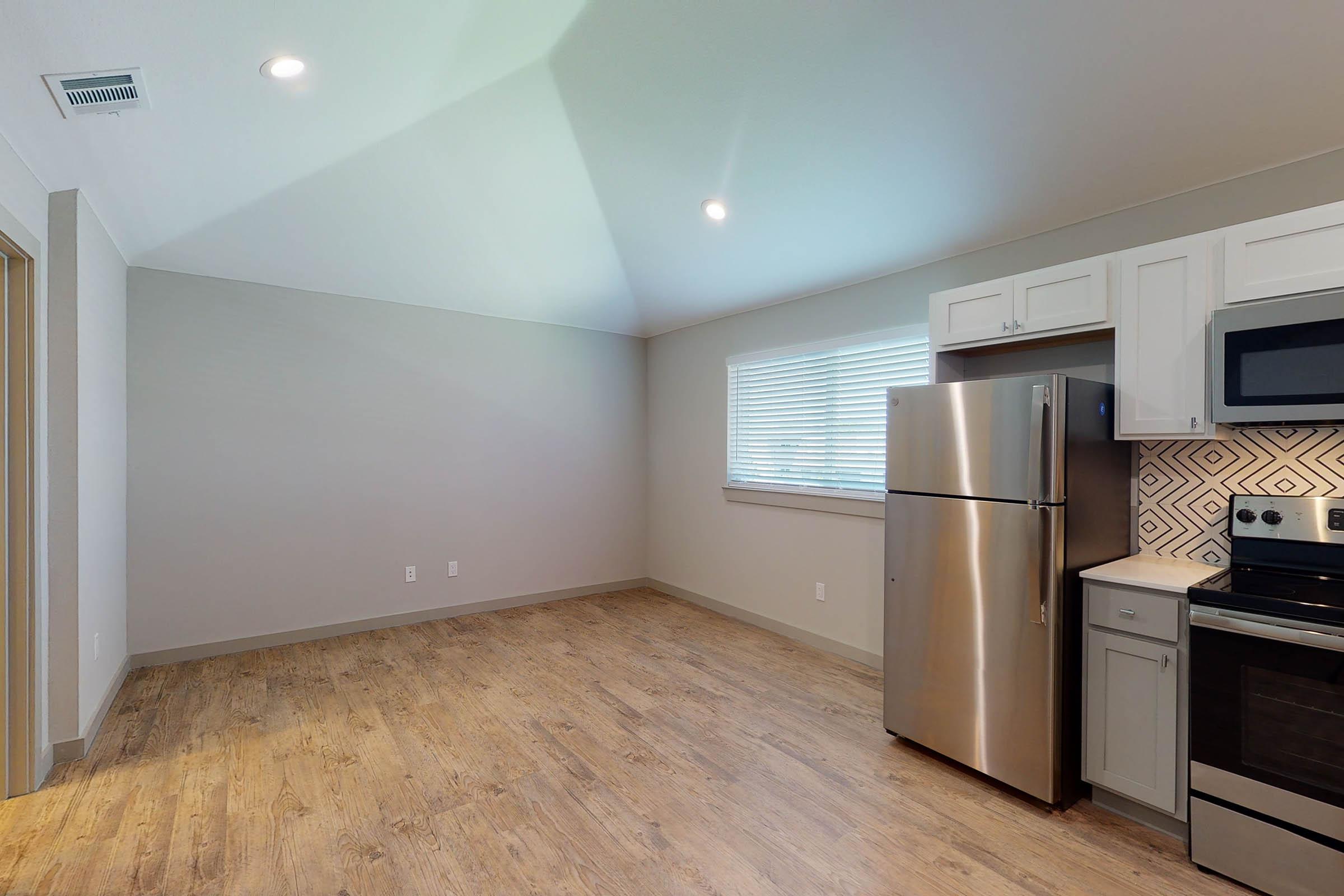 a vacant dining room and kitchen with wooden floors