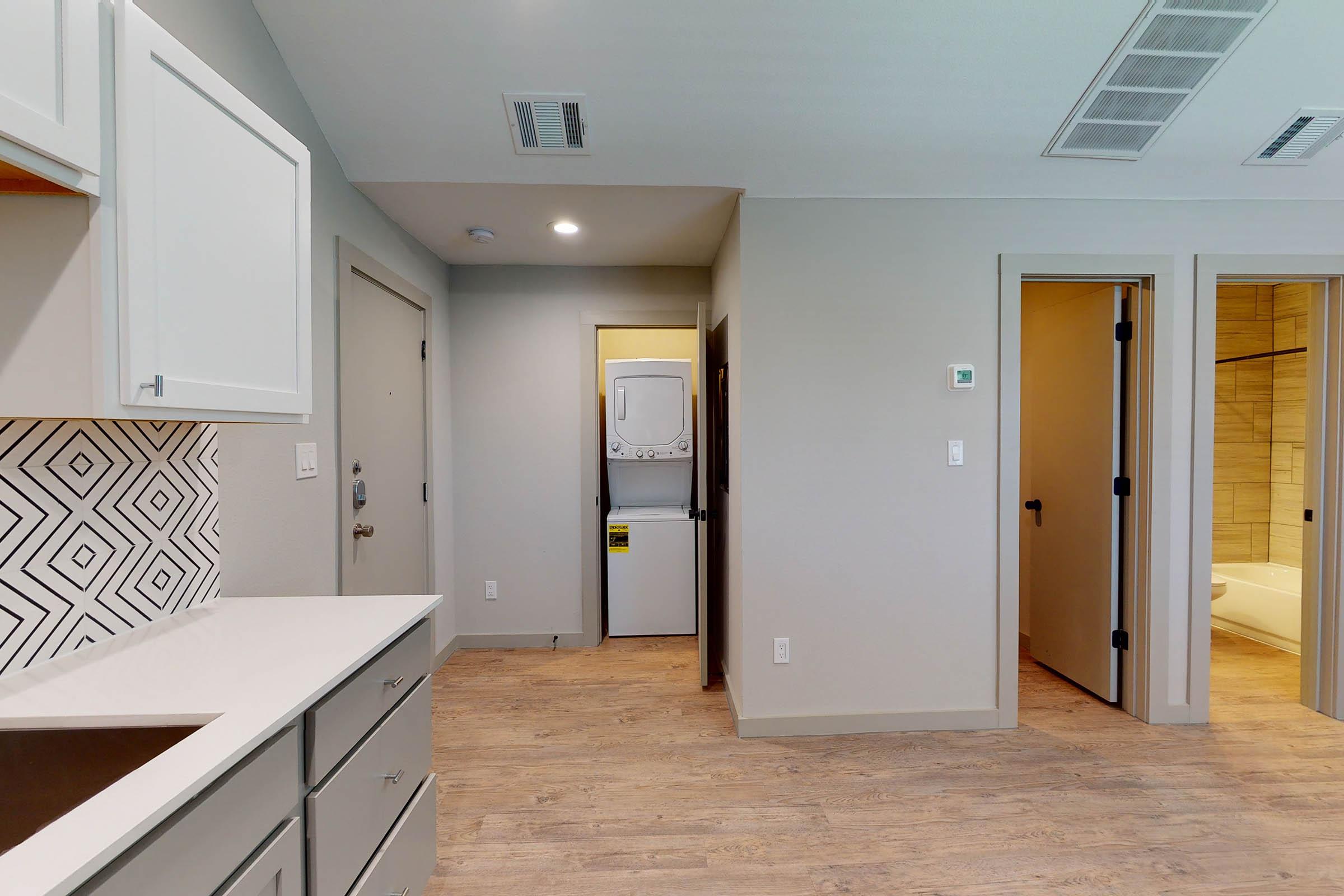 a vacant kitchen and hallway with wooden floors