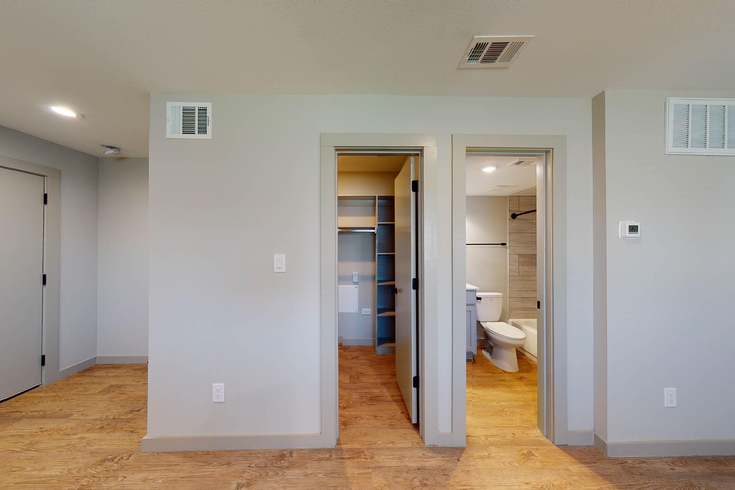 open closet and bathroom doors with wooden floorsq