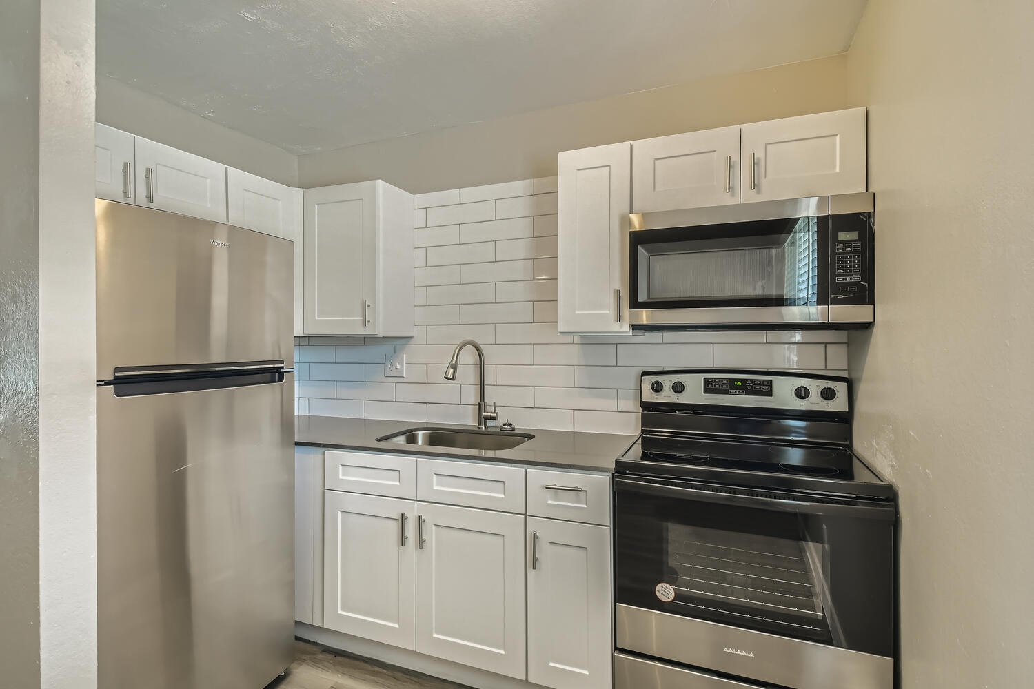 A small kitchen with grey quartz countertops and stainless steel appliances at Rise at the Palms.