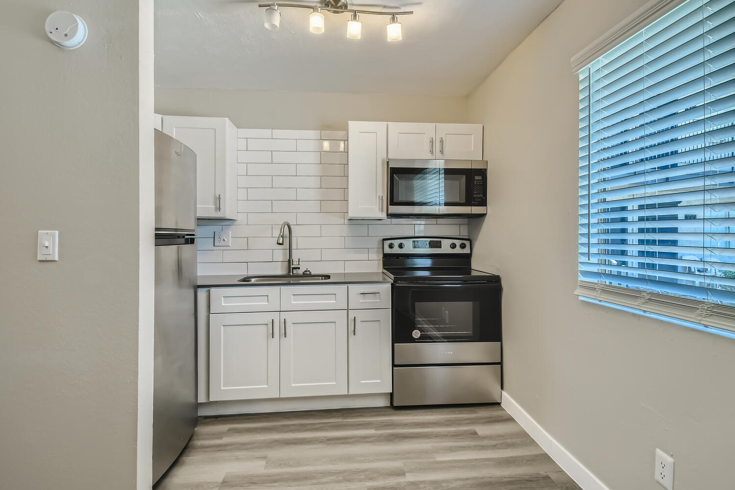 A kitchen with a window, shaker cabinets, and wood-style flooring at Rise at the Palms.