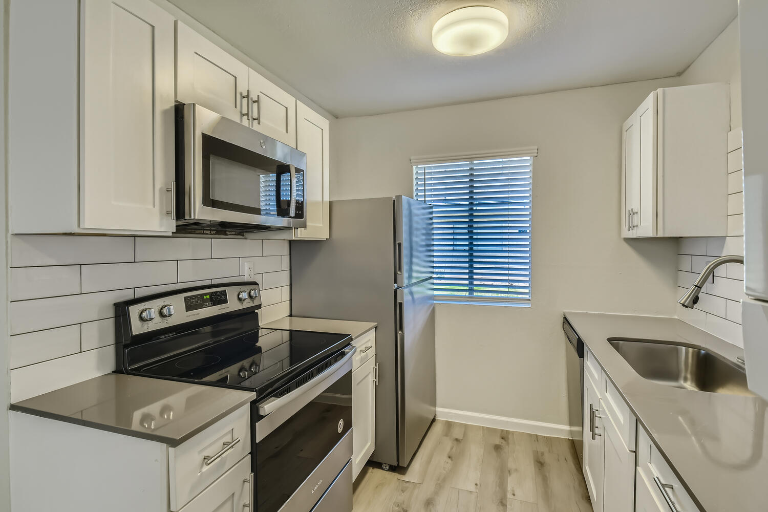 A kitchen with white shaker cabinets, stainless steel appliances and a window at Rise at the Palms. 