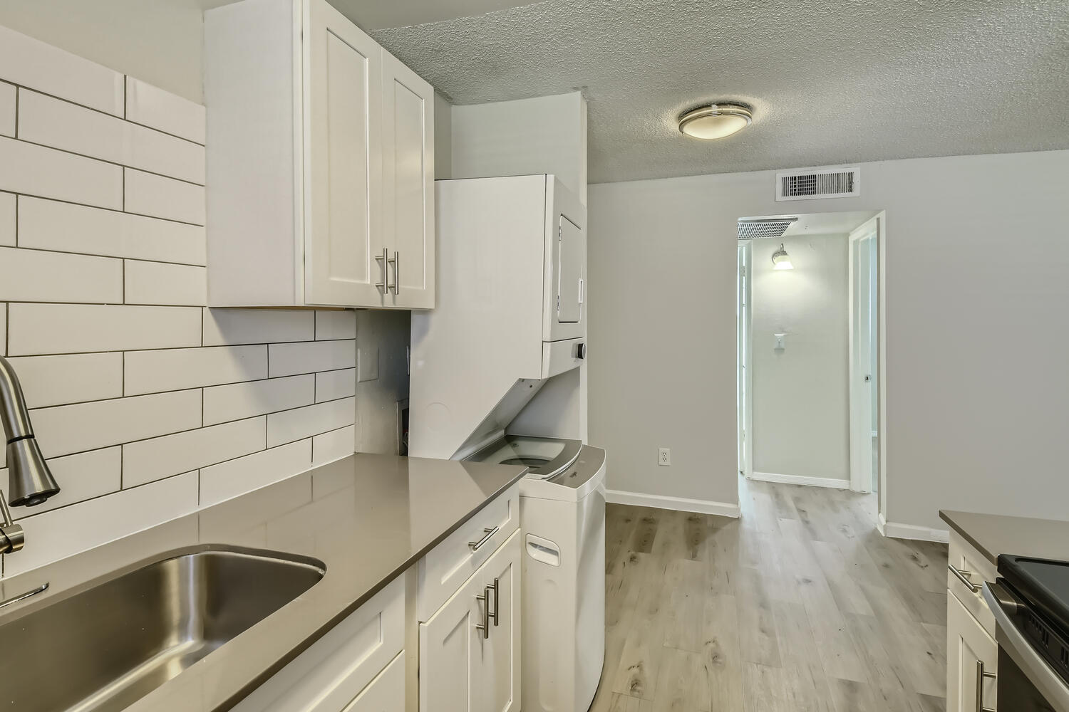 A kitchen with a washer and dryer and wood-style flooring at Rise at the Palms. 