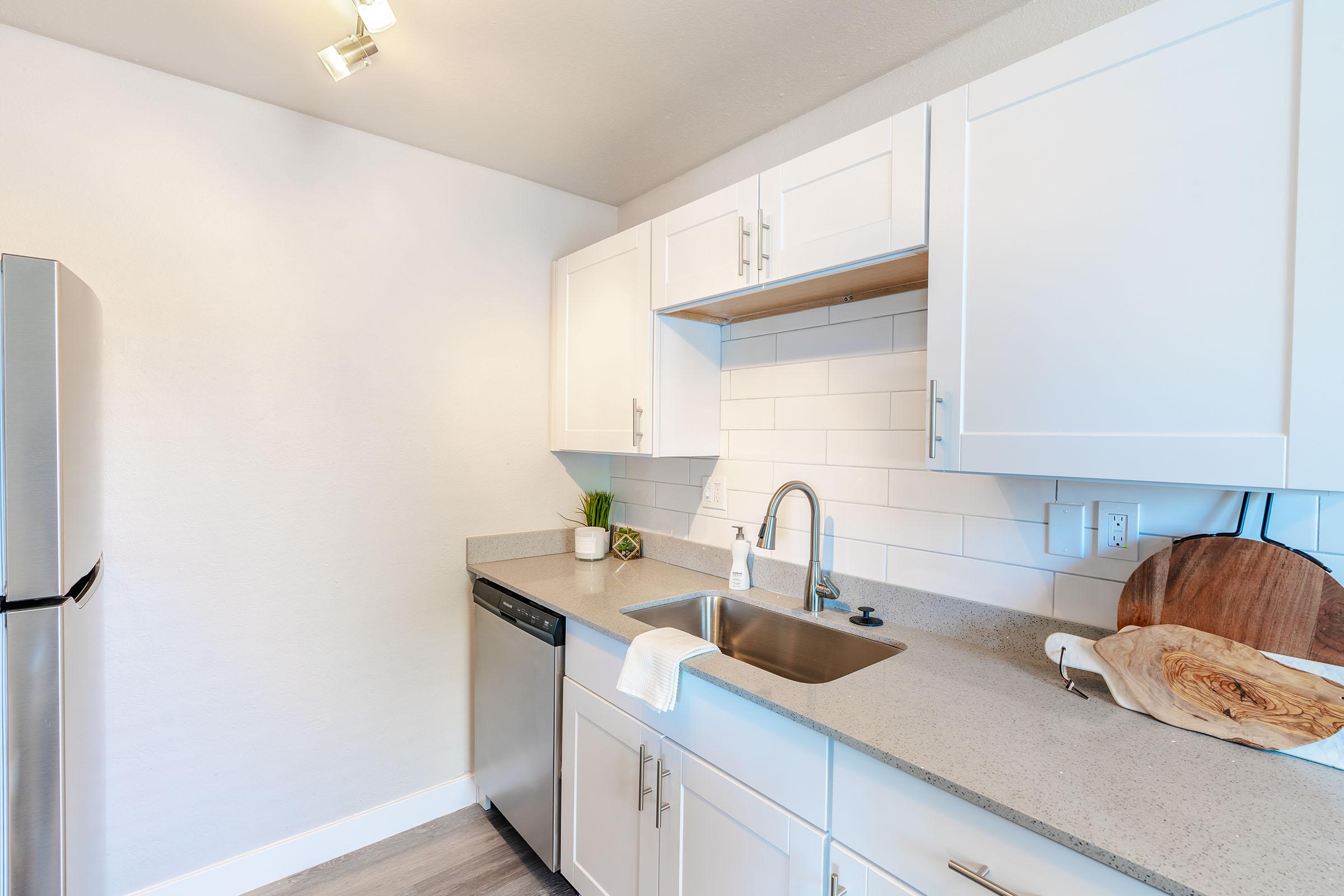 White kitchen cabinets over white tile backsplash and grey quartz countertops