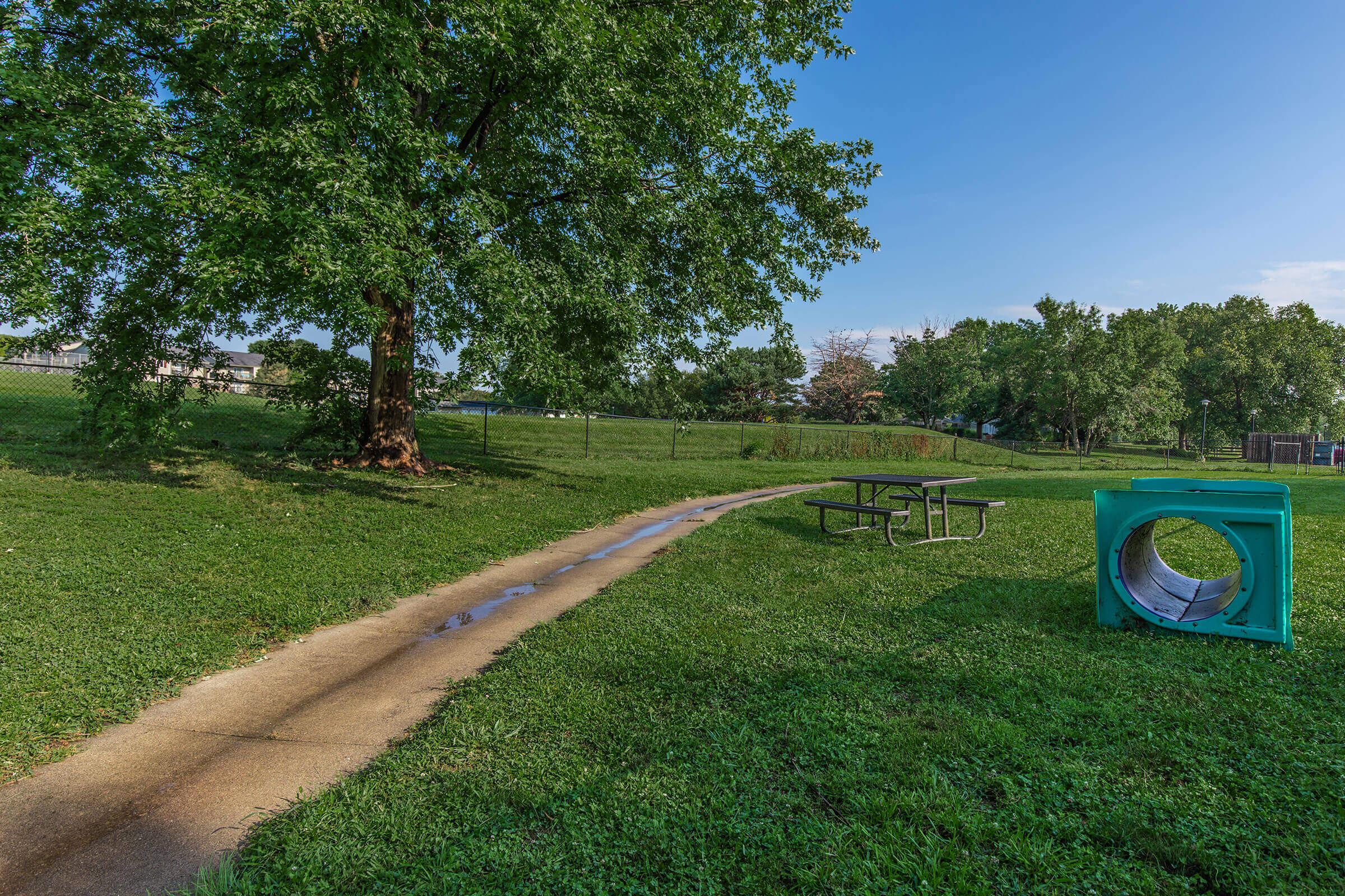 a large green field with trees in the background