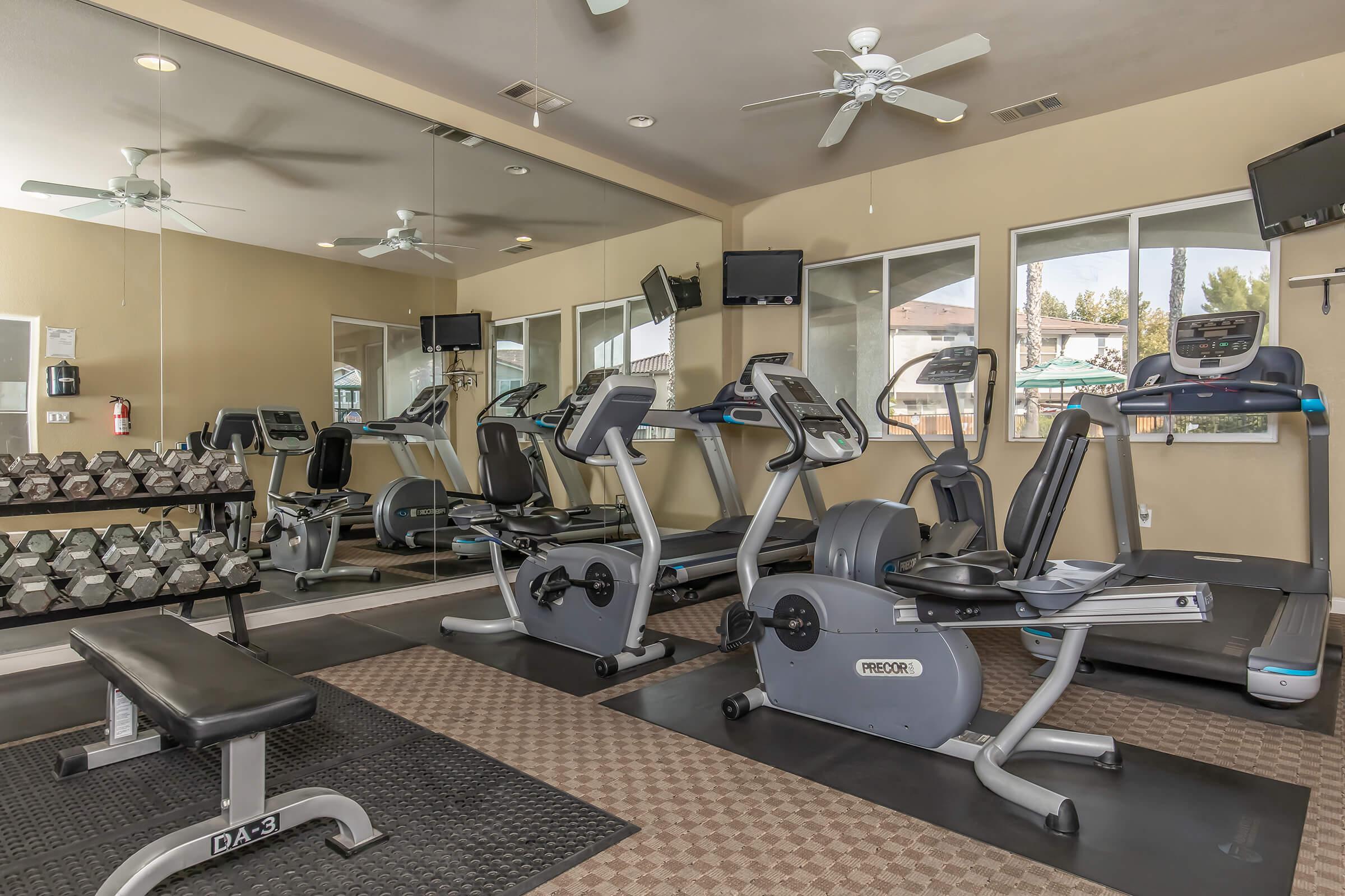 2 Bedroom Apartments In East Fresno CA - Parador Townhomes - Fitness Center Featuring Free Weights, Treadmills, Ellipticals, TV Screens, And Large Mirror