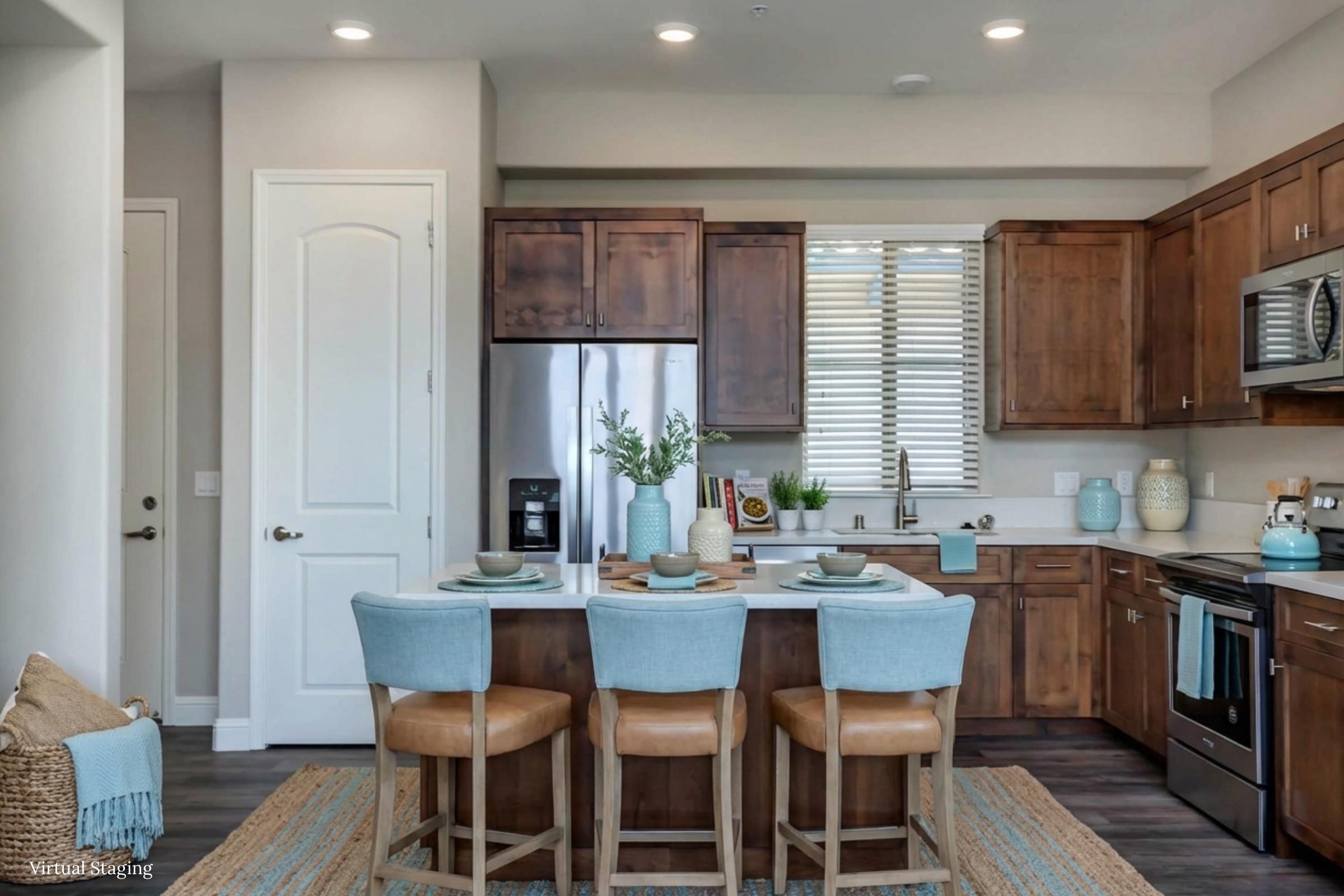 A modern kitchen with wooden cabinets and stainless steel appliances. A central island with four beige bar stools set for dining, featuring turquoise plates and glasses. The room is bright, with natural light streaming in through windows adorned with blinds, and decorative plants on the counter.