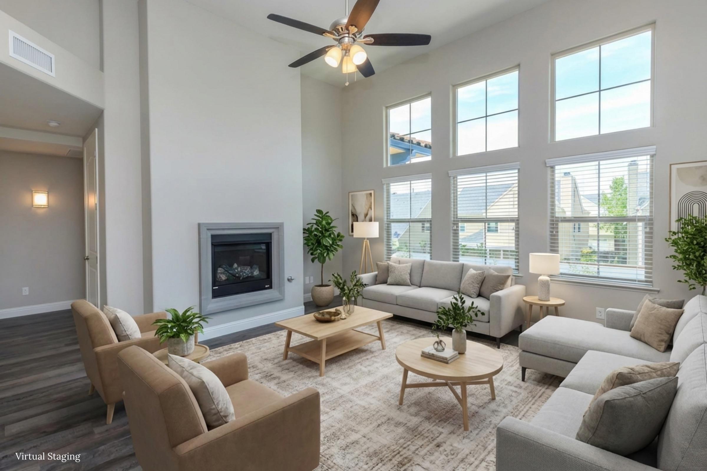A spacious living room featuring high ceilings, large windows with natural light, a modern gas fireplace, and stylish furniture. The area includes two sofas, a coffee table, and decorative plants, creating a warm and inviting atmosphere. The decor is contemporary and well-coordinated.
