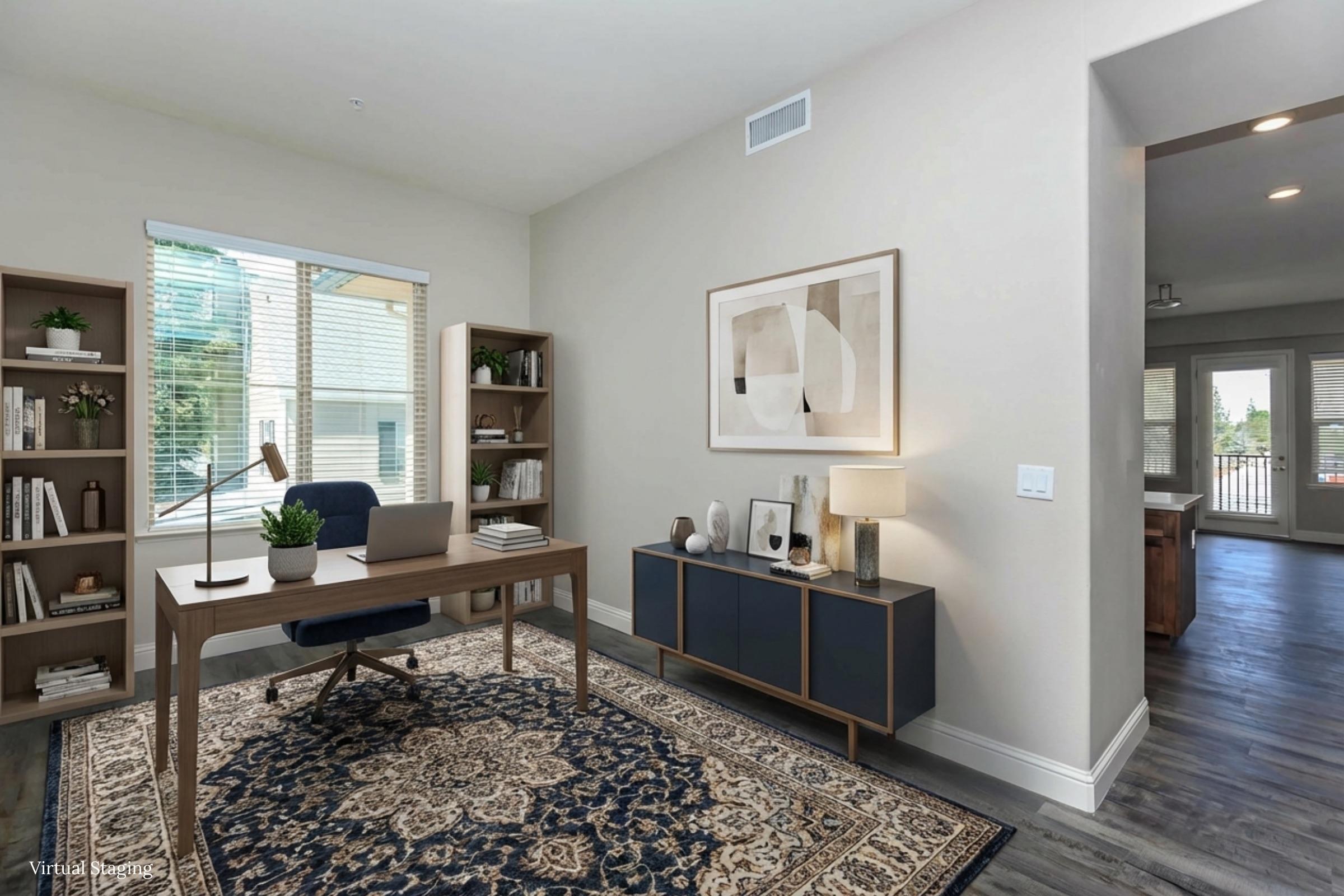 A modern home office featuring a wooden desk with a chair, a large window allowing natural light, and bookshelves filled with books. A decorative rug covers the floor, and there is a stylish cabinet with decorative items and a lamp. Warm tones and minimalistic decor create a welcoming atmosphere.