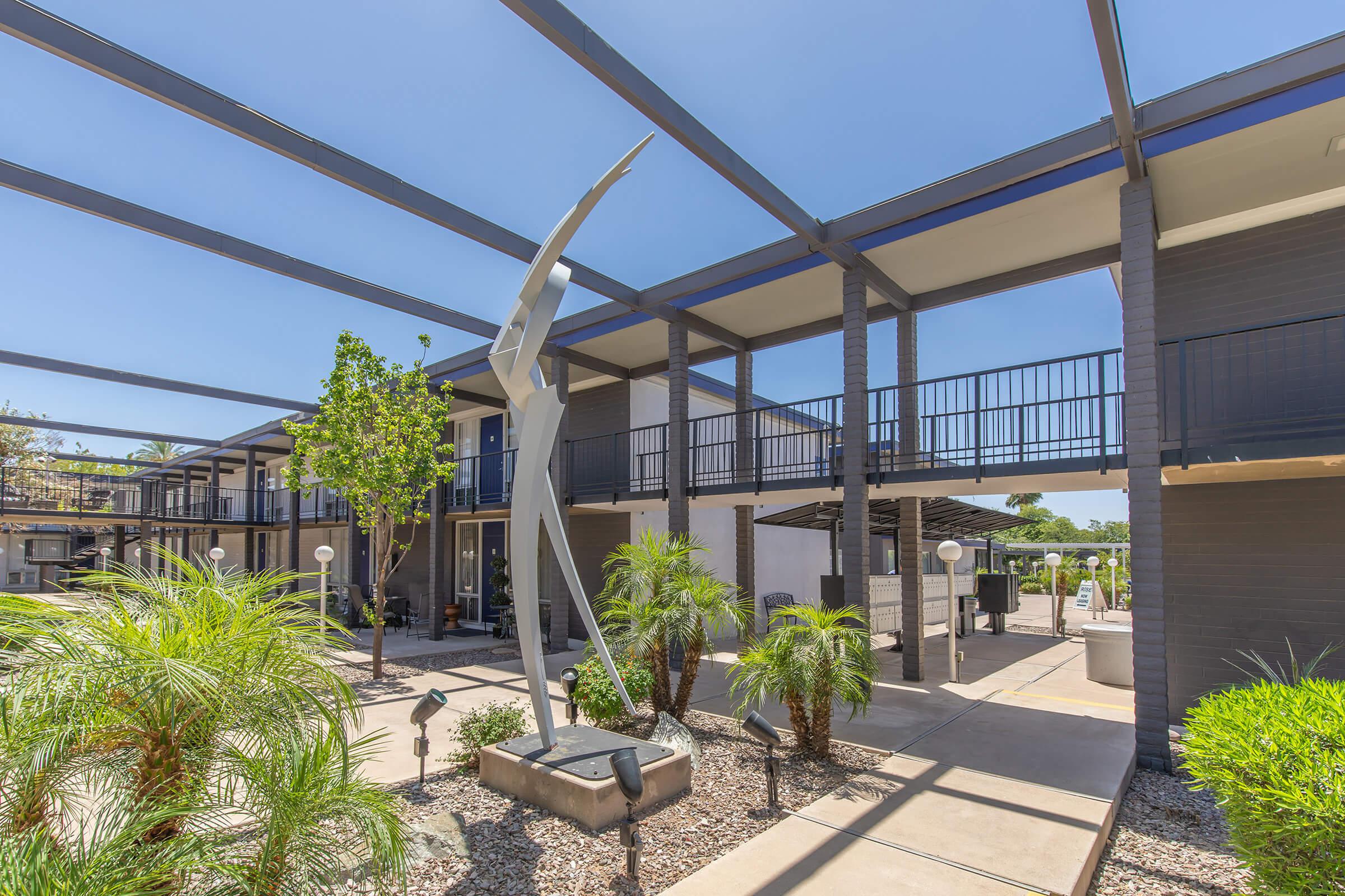 Outdoor modern art sculpture surrounded by aRise Biltmore apartment complex walkway and overhead beams