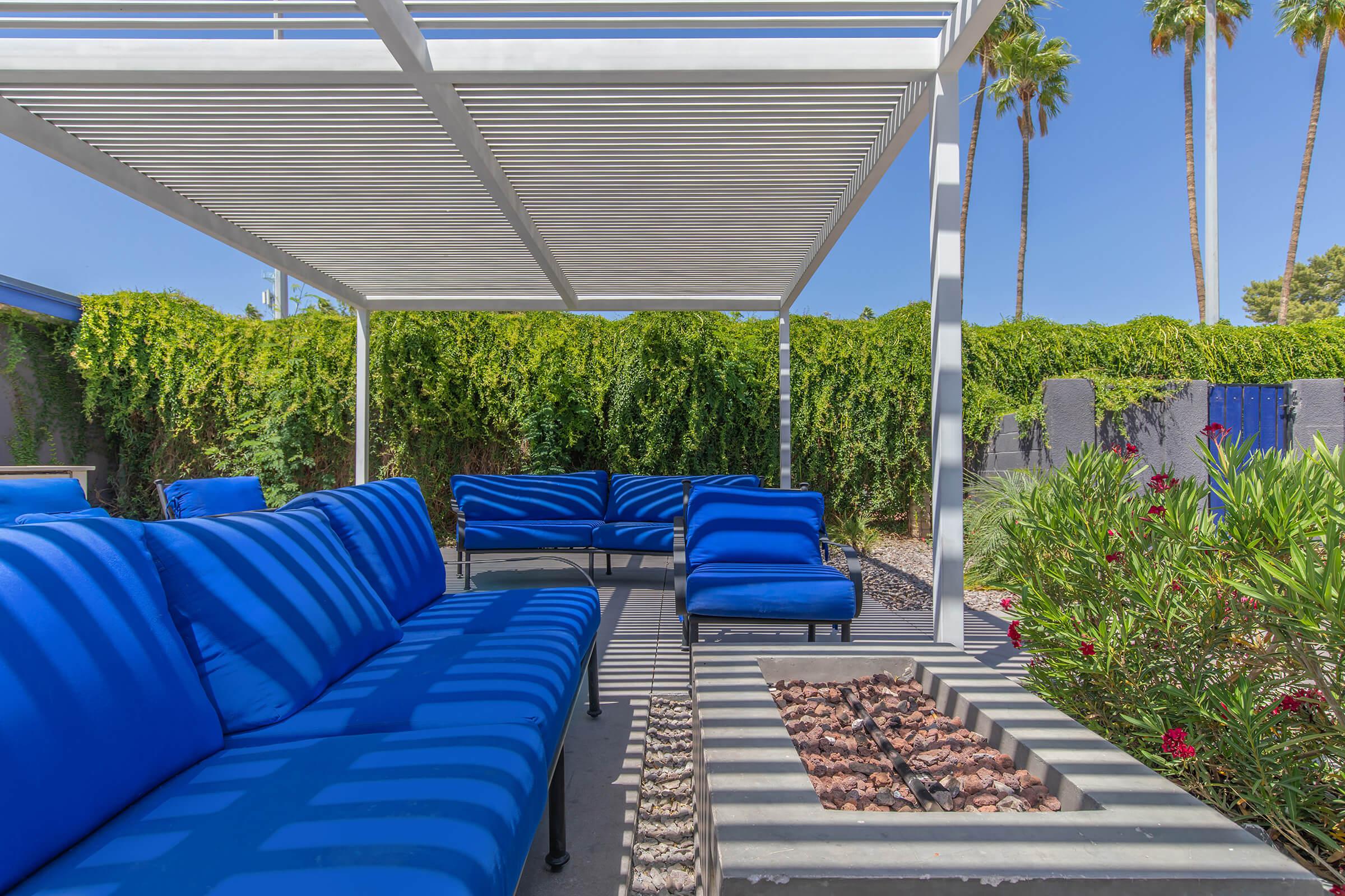 Outdoor patio area with blue lounge couch seating around an electric fire pit at Rise Biltmore