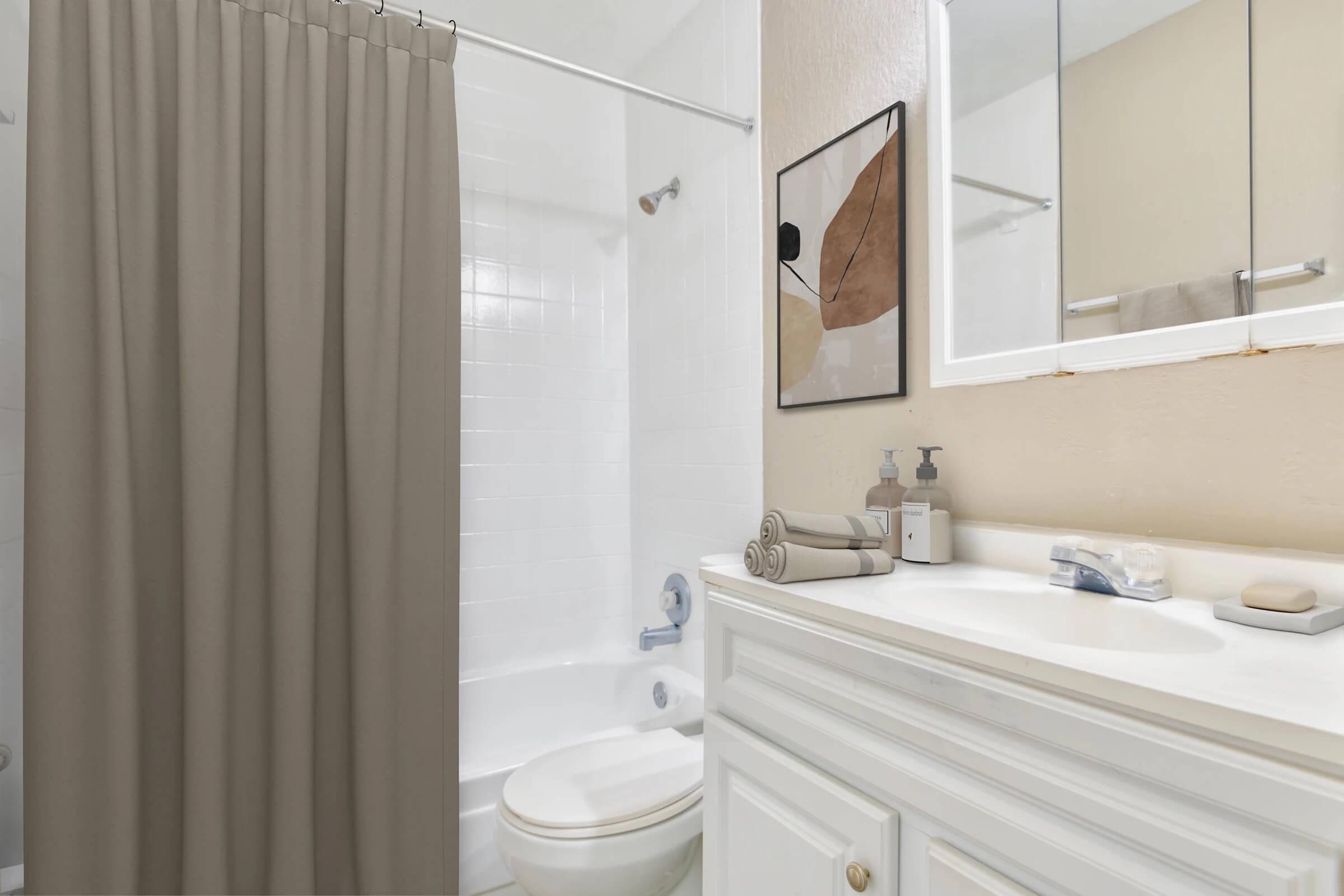 A clean and modern bathroom featuring a white bathtub with a beige shower curtain, a sleek vanity with a mirror, and neatly arranged toiletries. The walls are painted a soft color, complemented by a decorative wall art piece adding a touch of style. Ample natural light enhances the overall bright appearance.