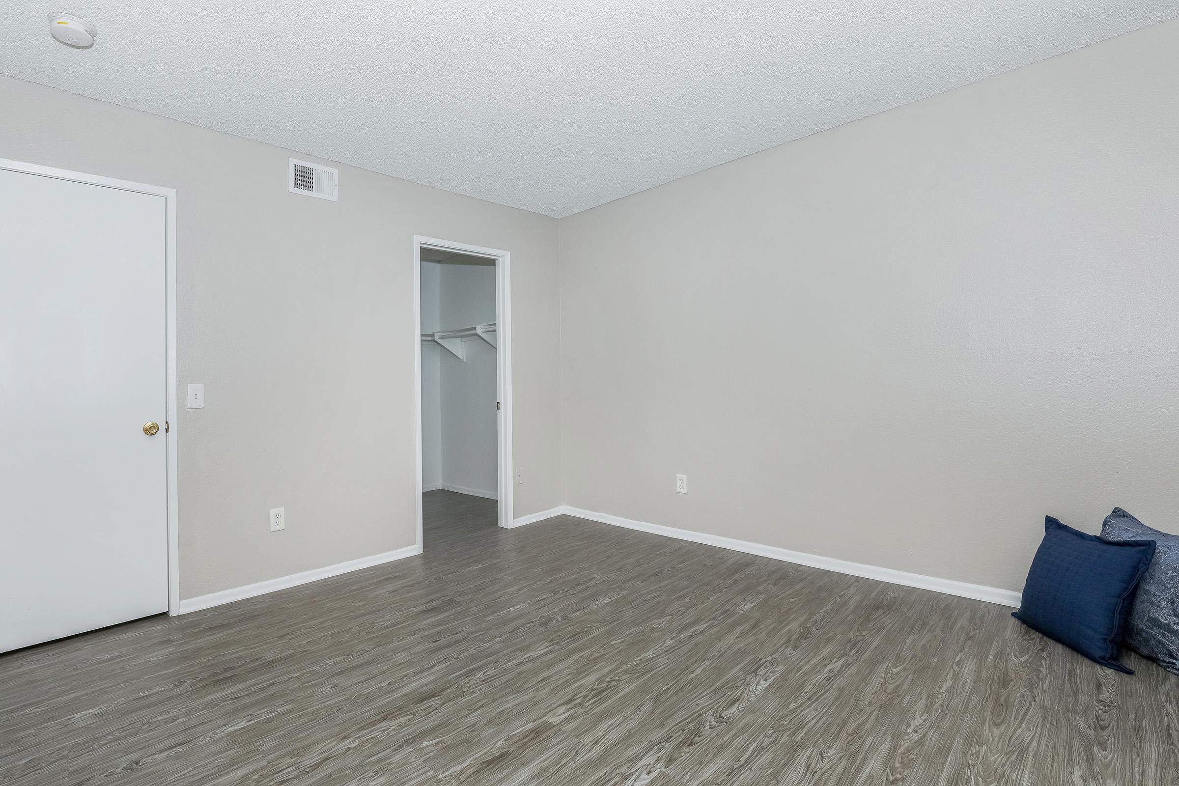 1 Bedroom Apartments in San Bernardino, CA - Creekside Village - Spacious Bedroom with Dark Wood-Like Flooring, Large Closet, and Textured Ceiling.