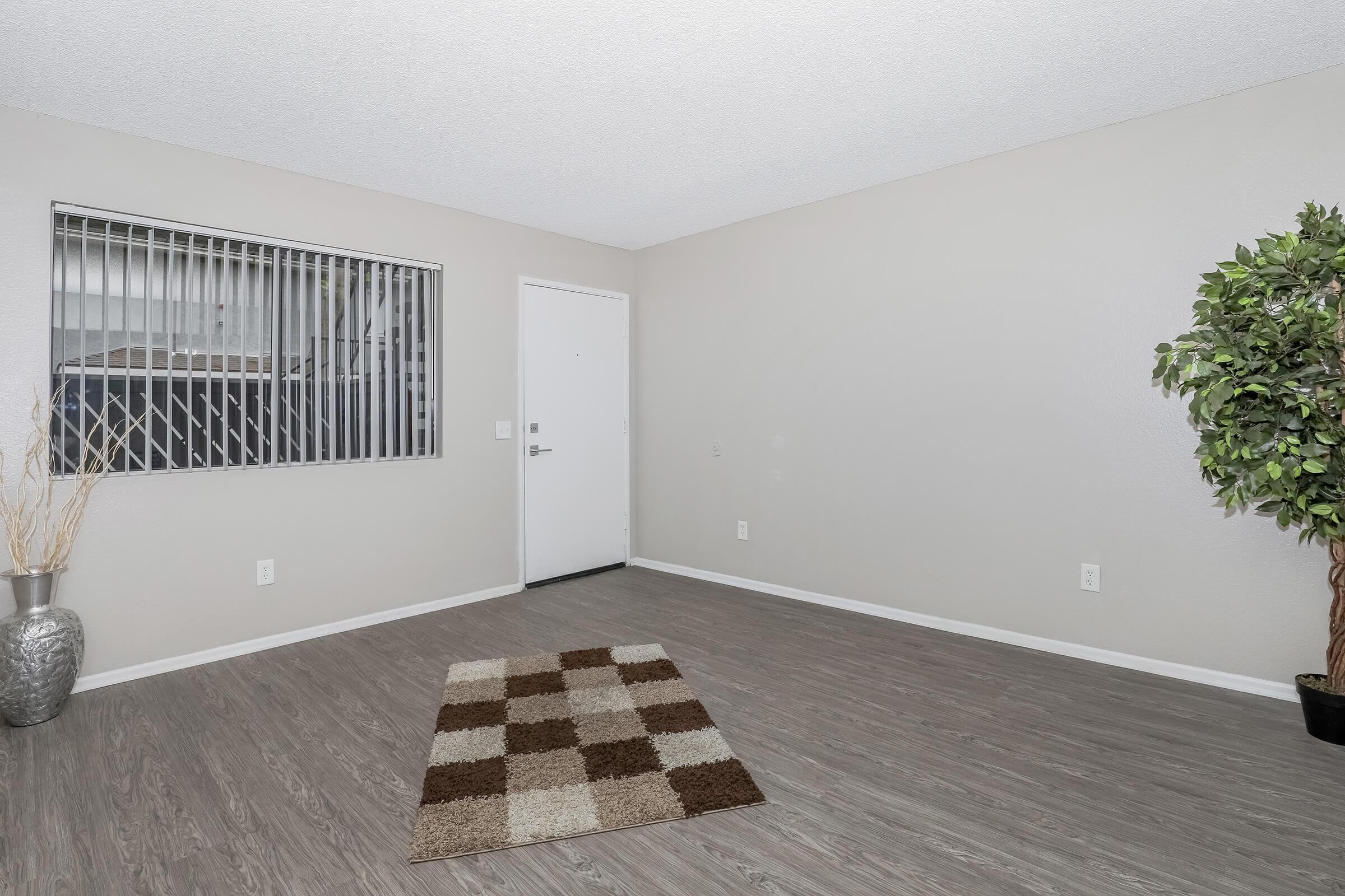 2 Bedroom Apartments in San Bernardino CA - Creekside-Village - Open Living Room with Large Window, Window Blinds, Wood-Like Flooring, and Textured Ceilings