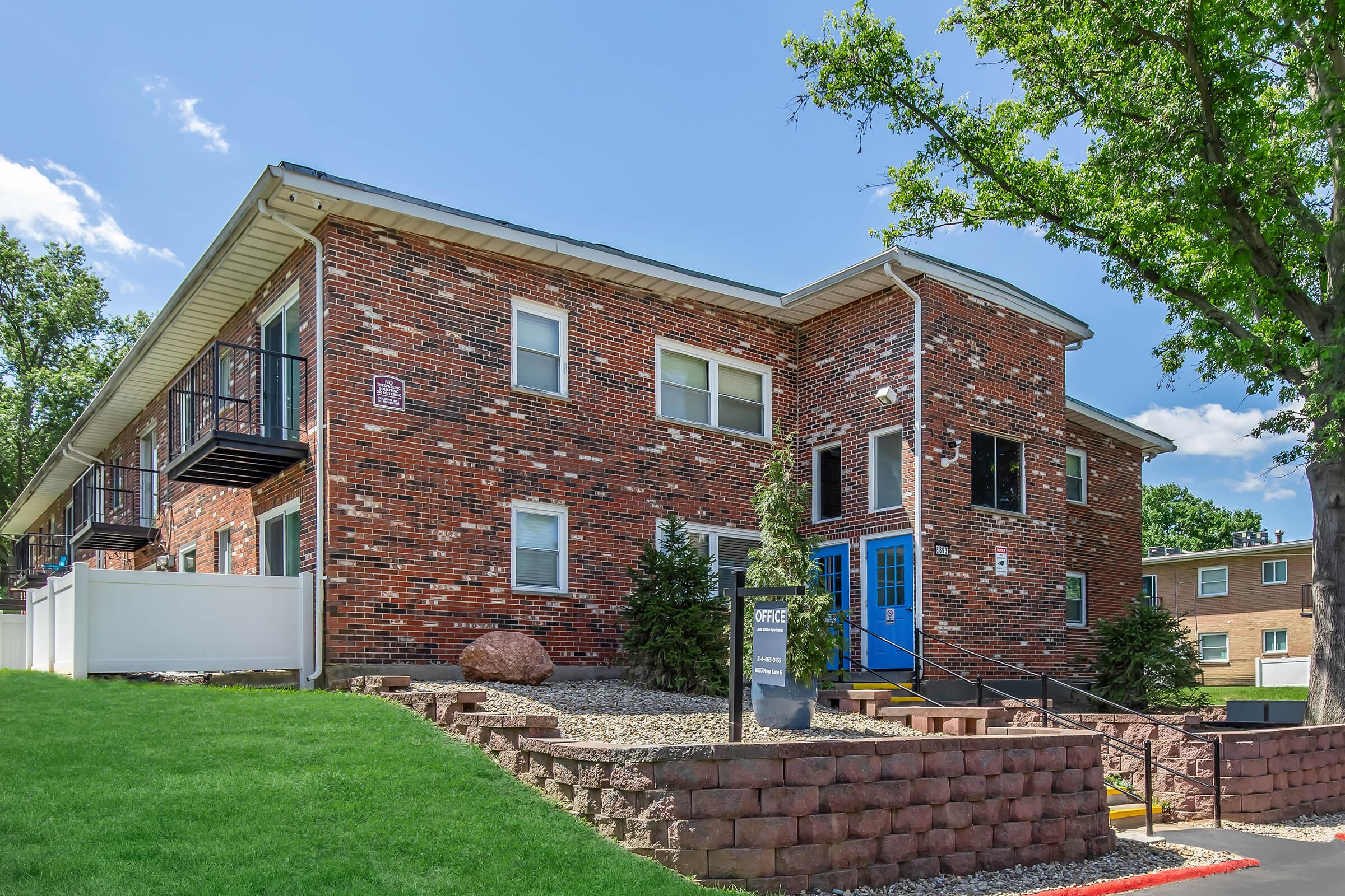 a large brick building with grass in front of a house