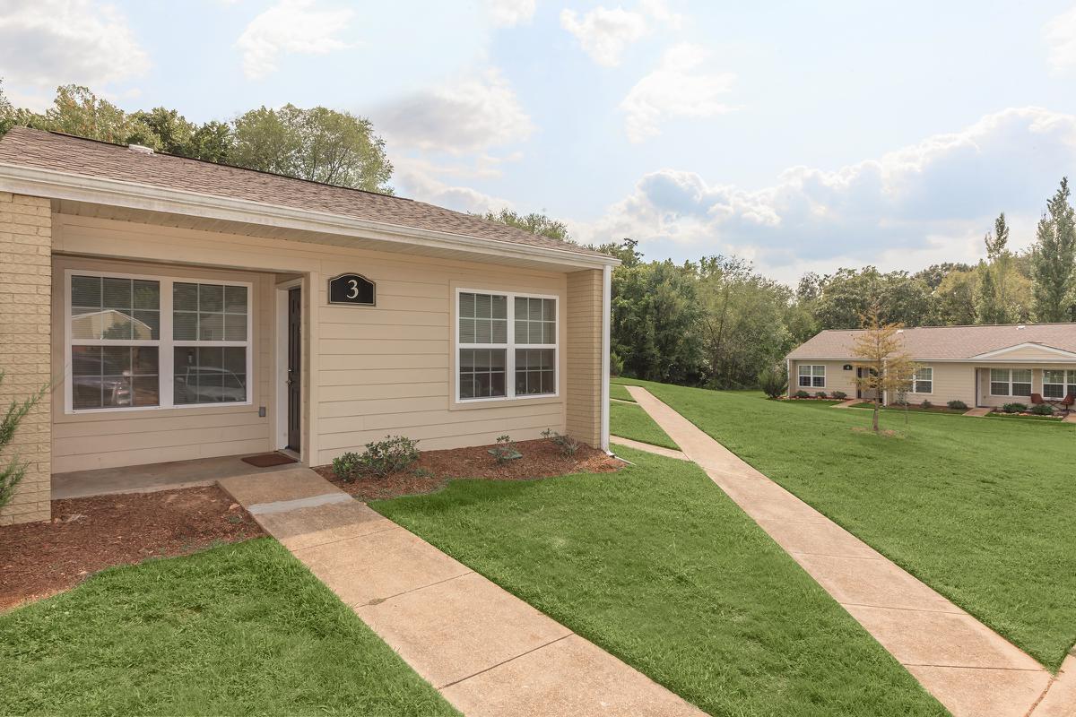 a large brick building with grass in front of a house