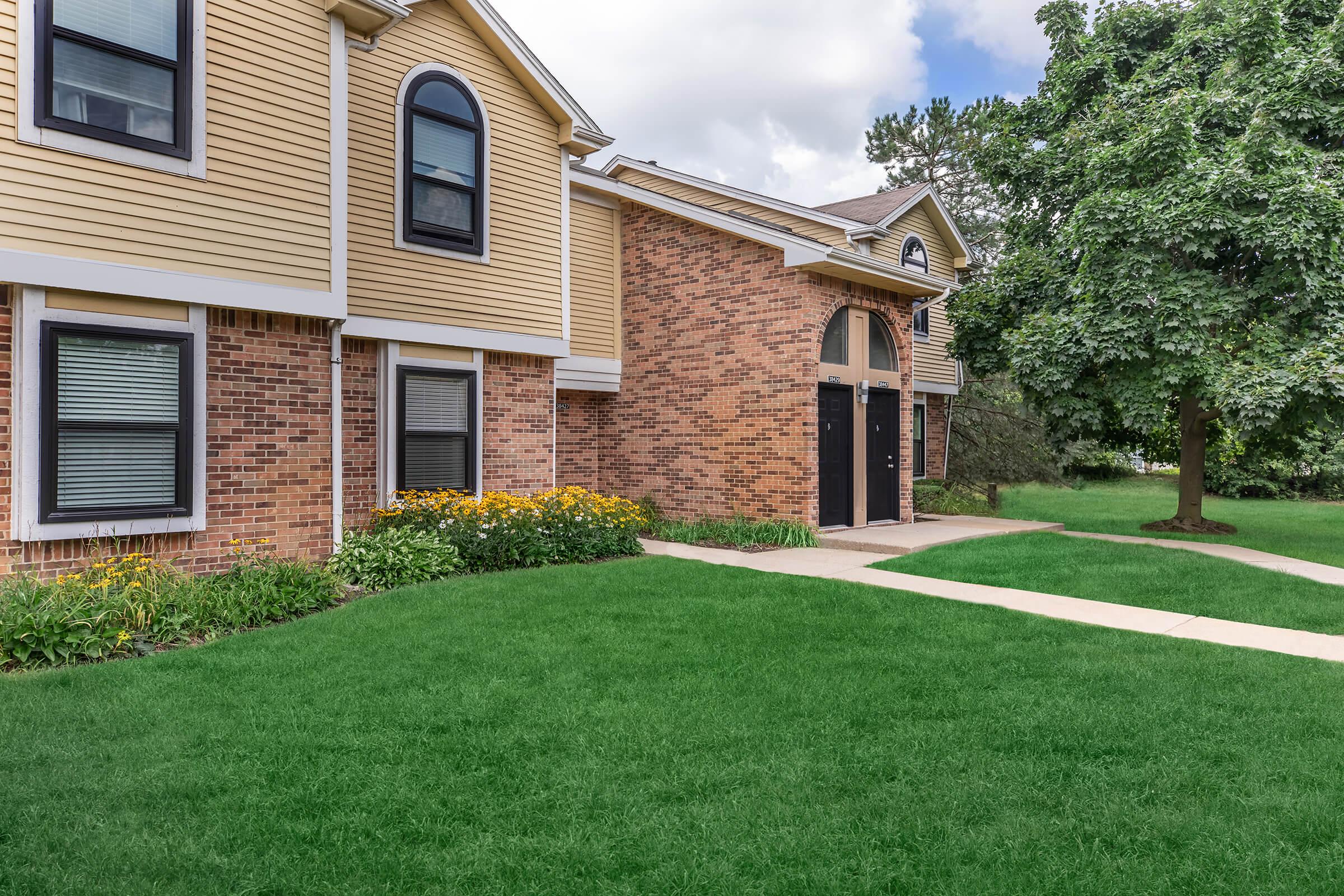 a large brick building with grass in front of a house