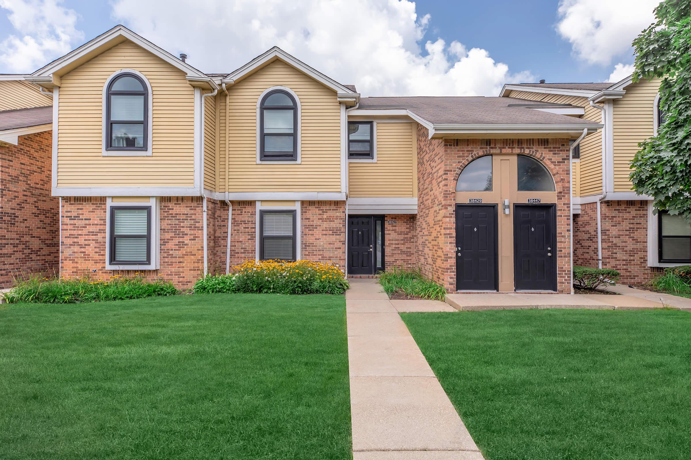 a house with a lawn in front of a brick building