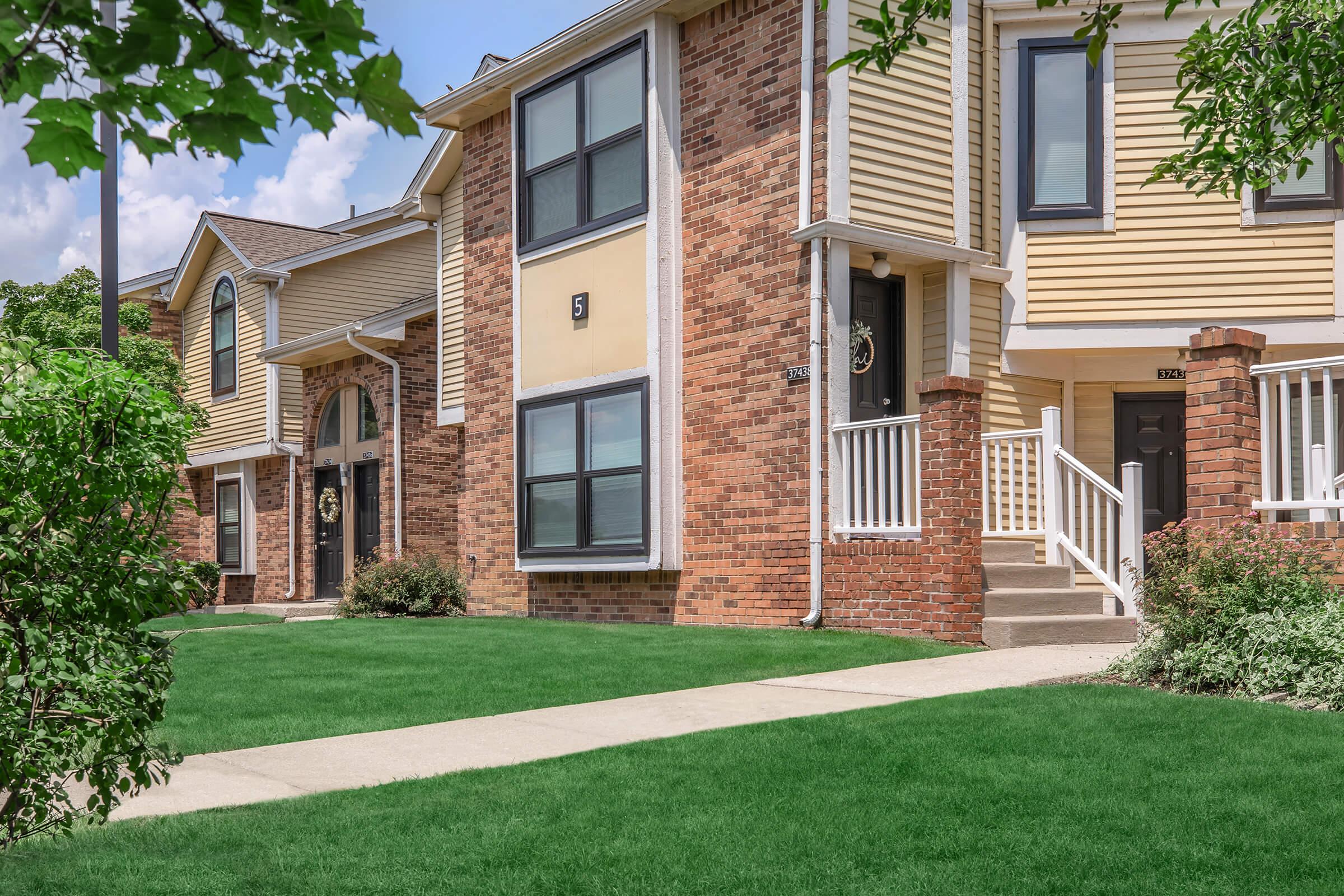 a house with a lawn in front of a brick building