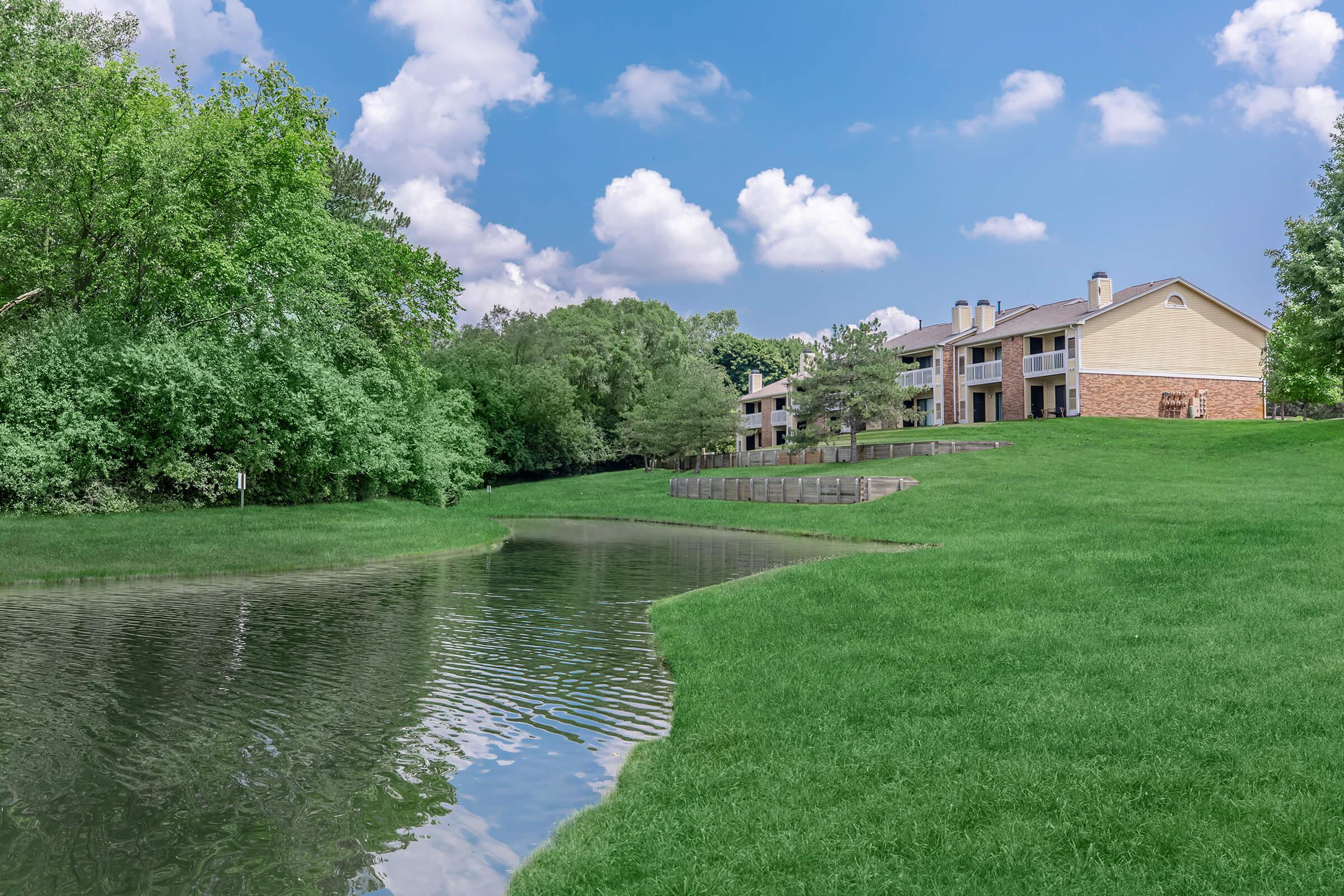 a lake surrounded by green grass and trees