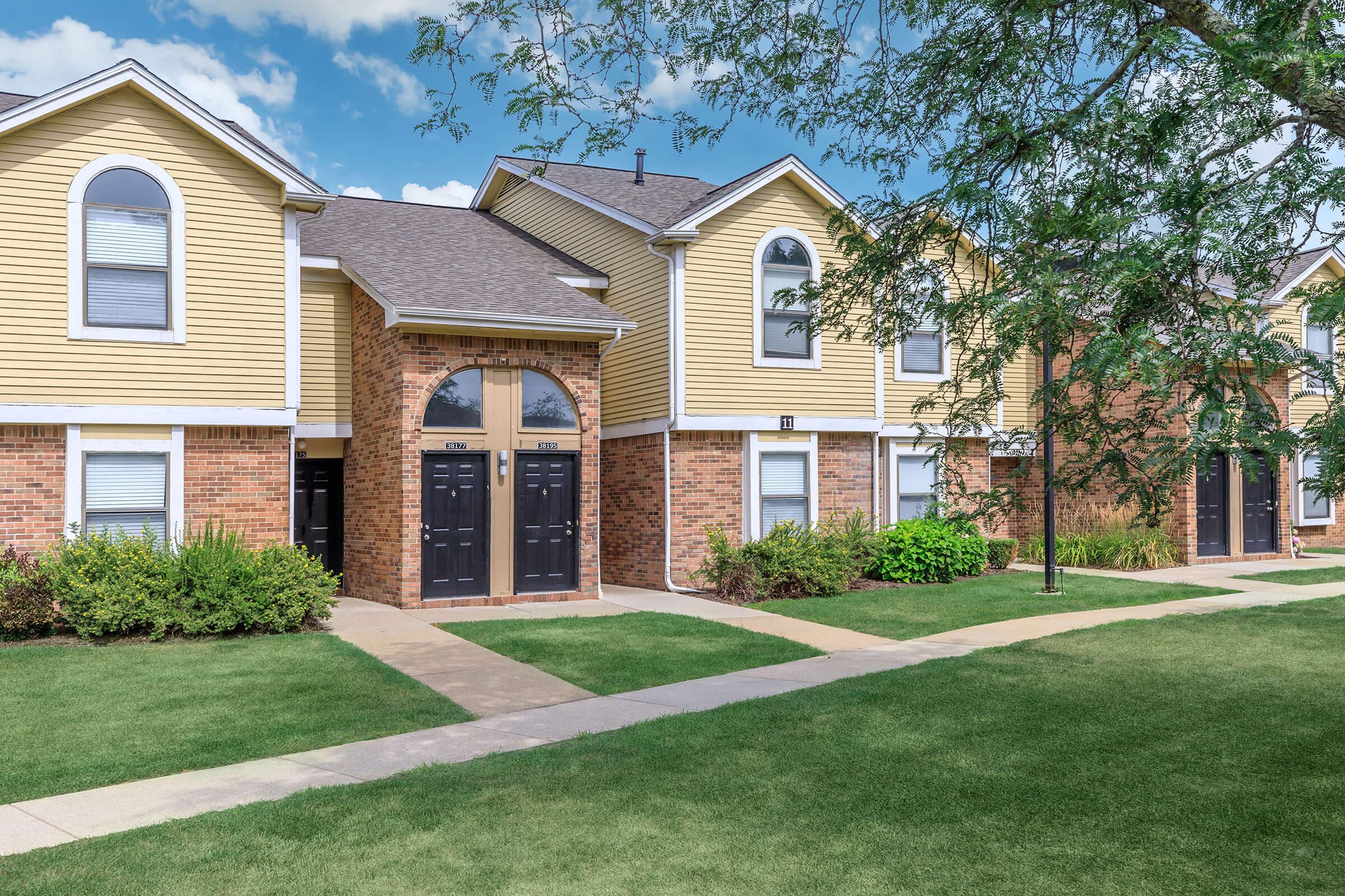 a large brick building with grass in front of a house