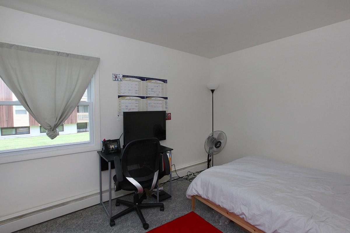 a bedroom with a bed and a chair in a room