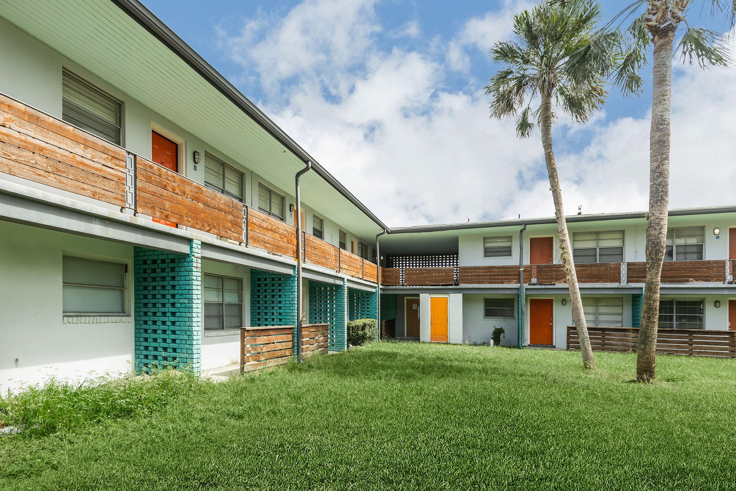 a large brick building with green grass