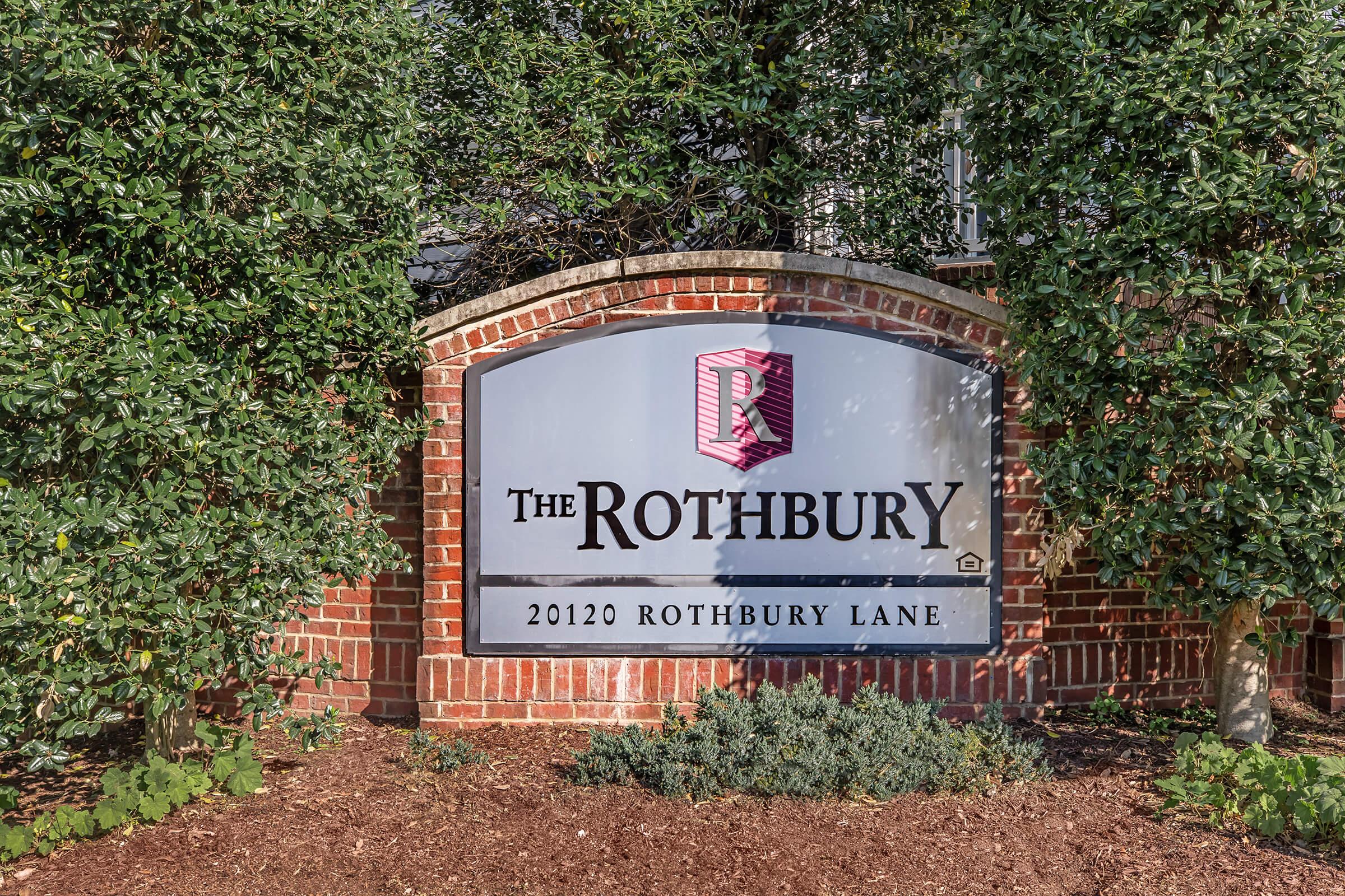 Sign for "The Rothbury" located at 20120 Rothbury Lane. The sign is set against a brick background, surrounded by greenery and landscaping.