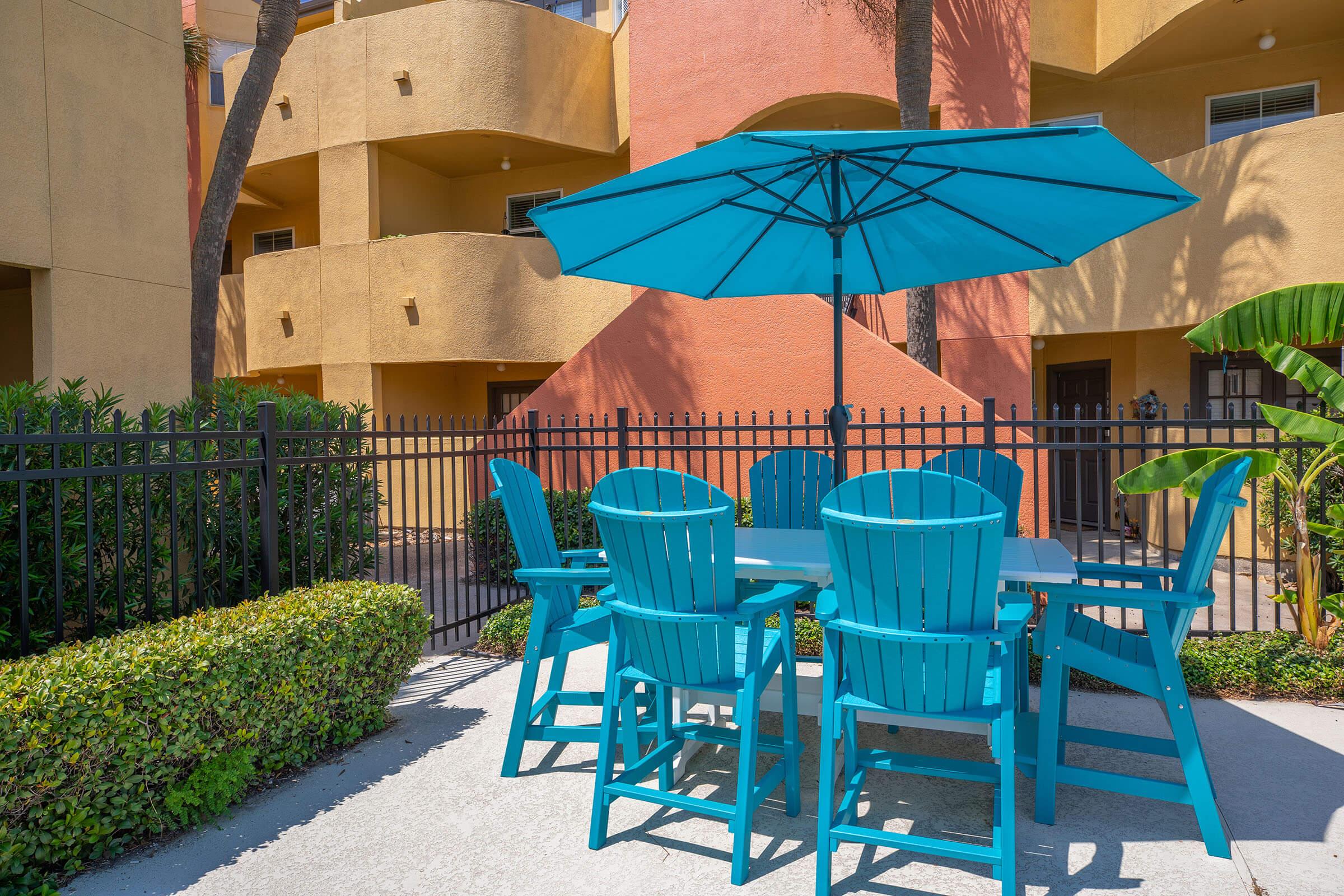 a green chair at a table with a blue umbrella