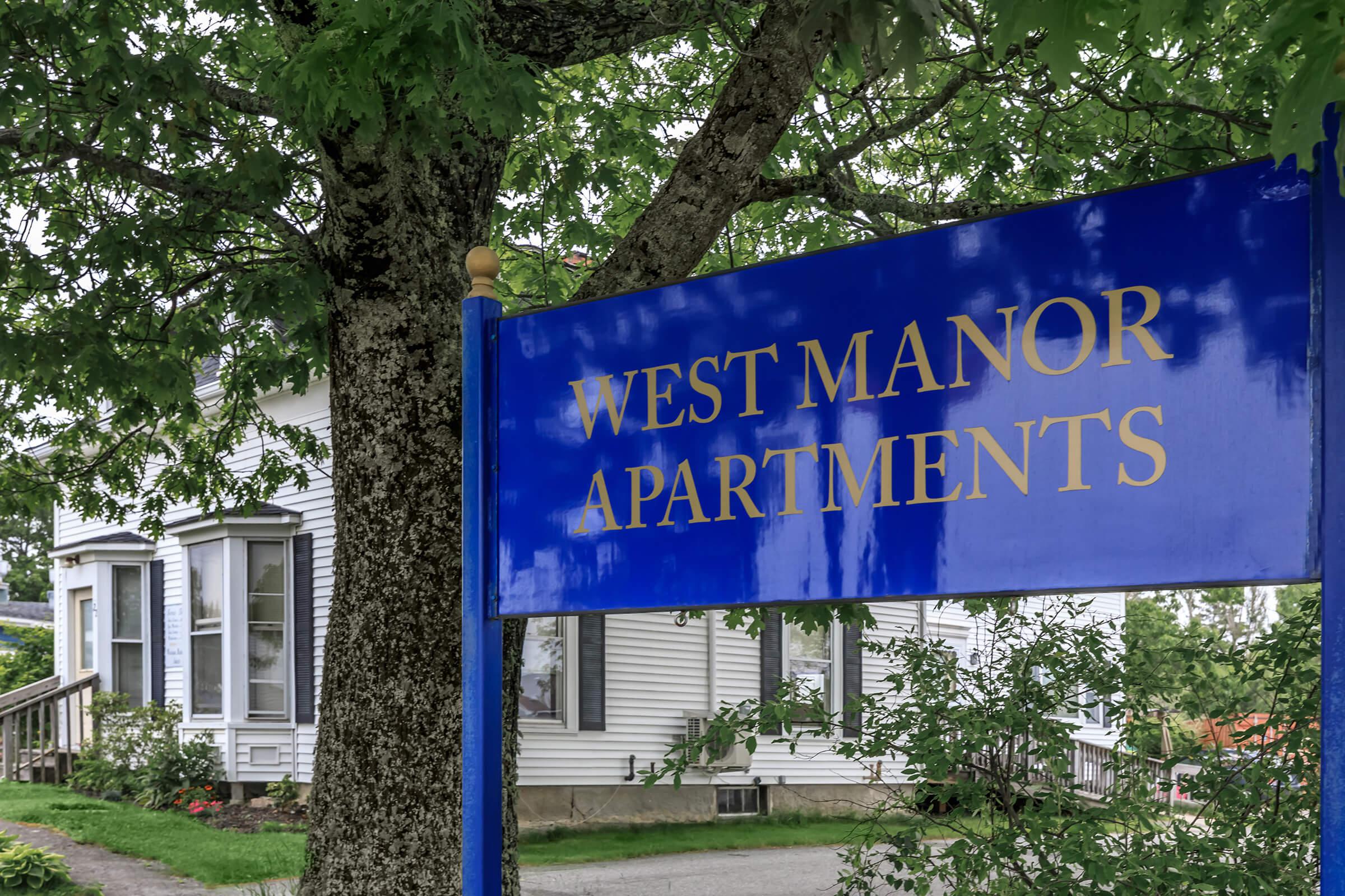 a blue sign in front of a tree