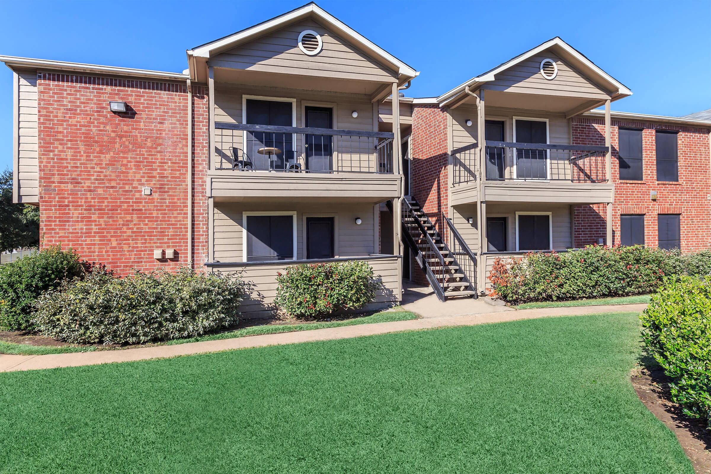 a house with a lawn in front of a brick building