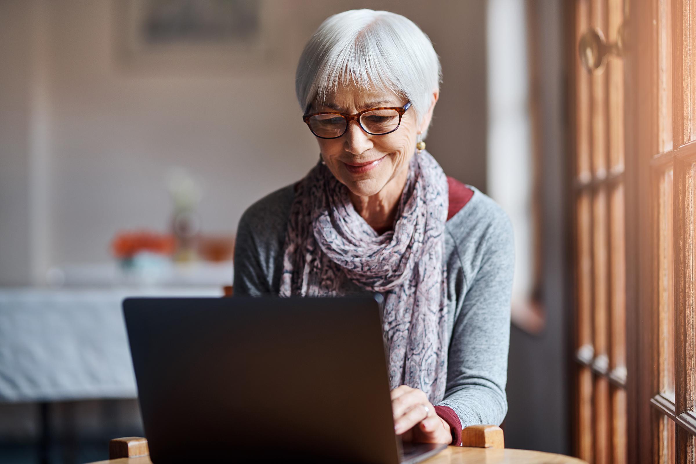 a person sitting at a table using a laptop computer